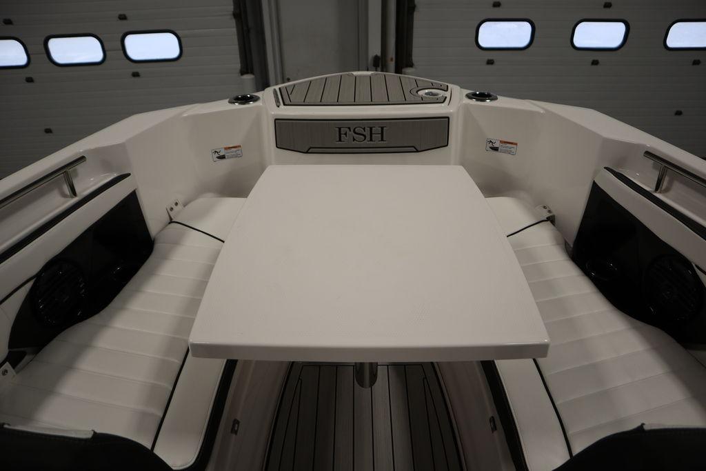 2026 Yamaha Boats 255 FSH Sport E interior with seating and table in a garage setting.