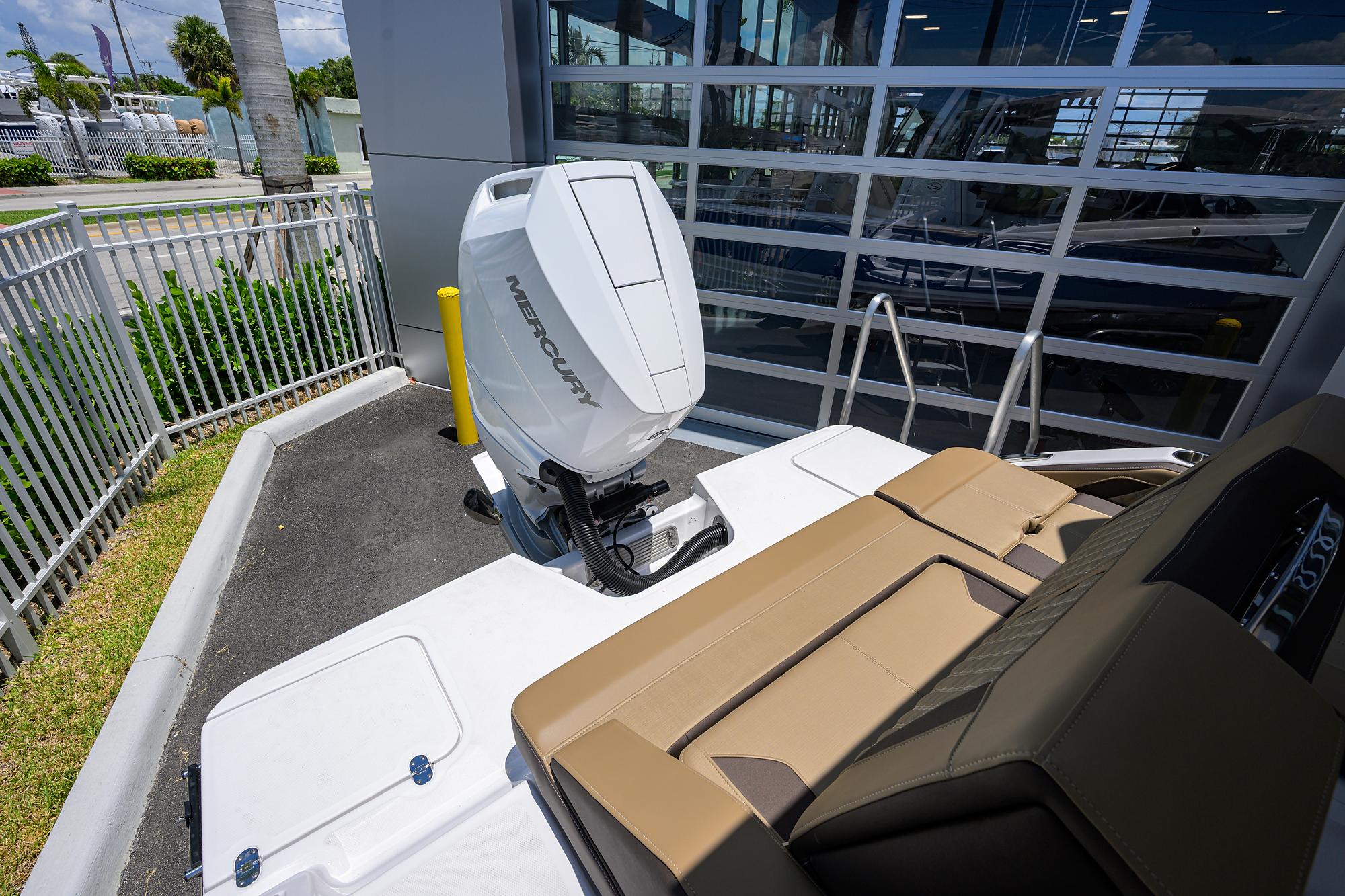 2026 Monterey Elite 27 OB boat with Mercury outboard engine, parked near a modern building.