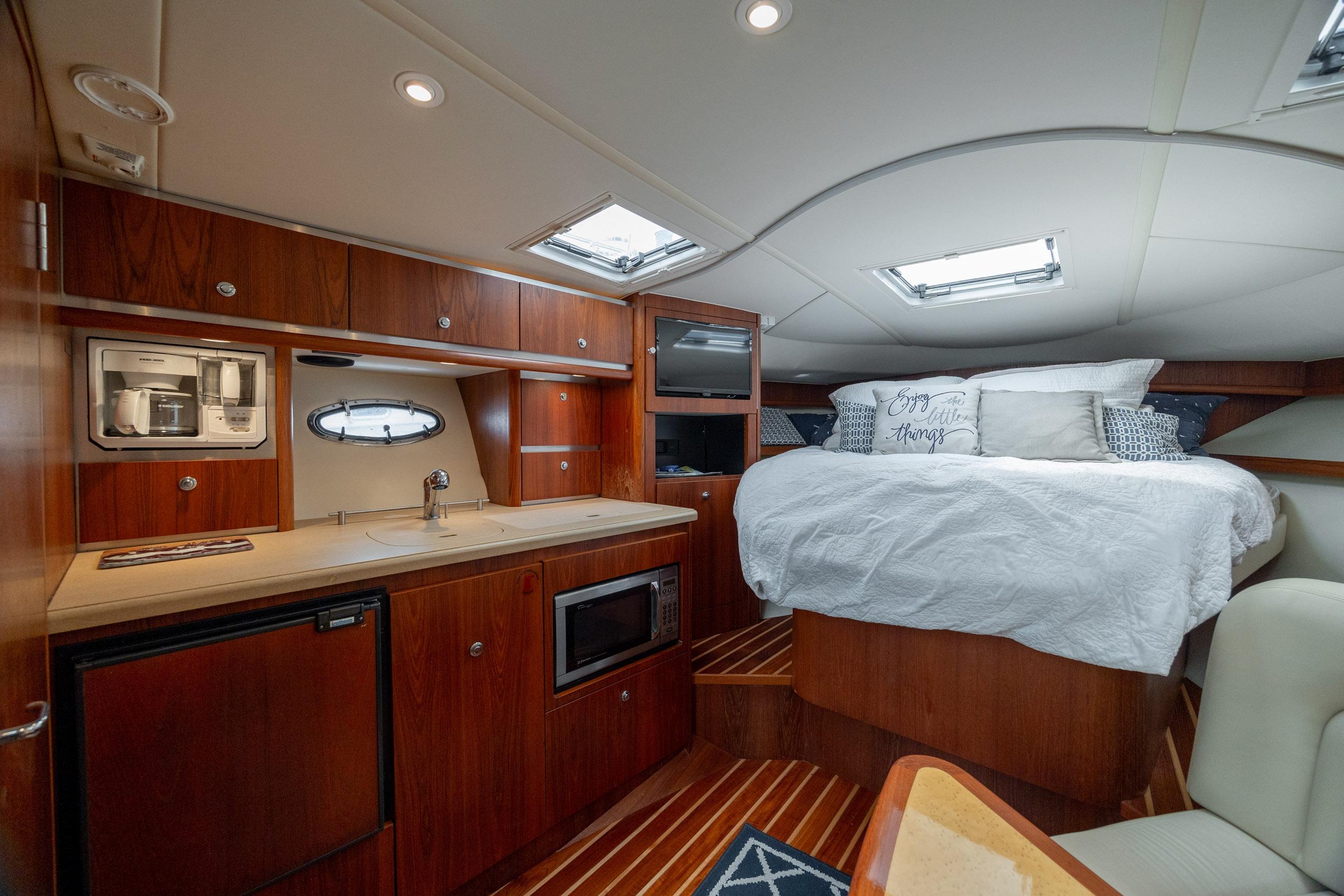 Luxurious interior of 2004 Tiara Yachts 3200 Open with cozy bed and kitchenette.