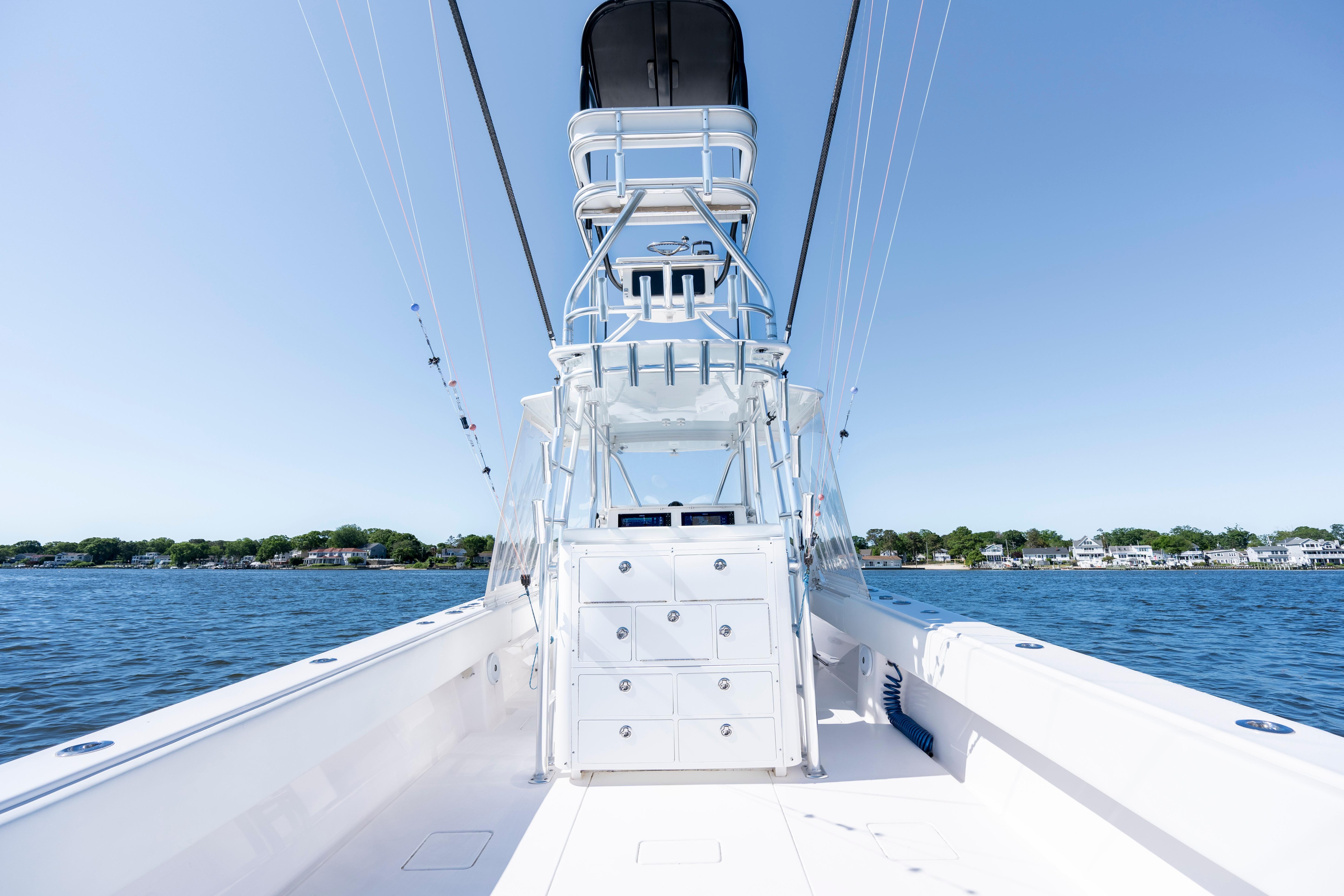 2015 Contender 39 ST boat on calm water, clear sky, coastal background.