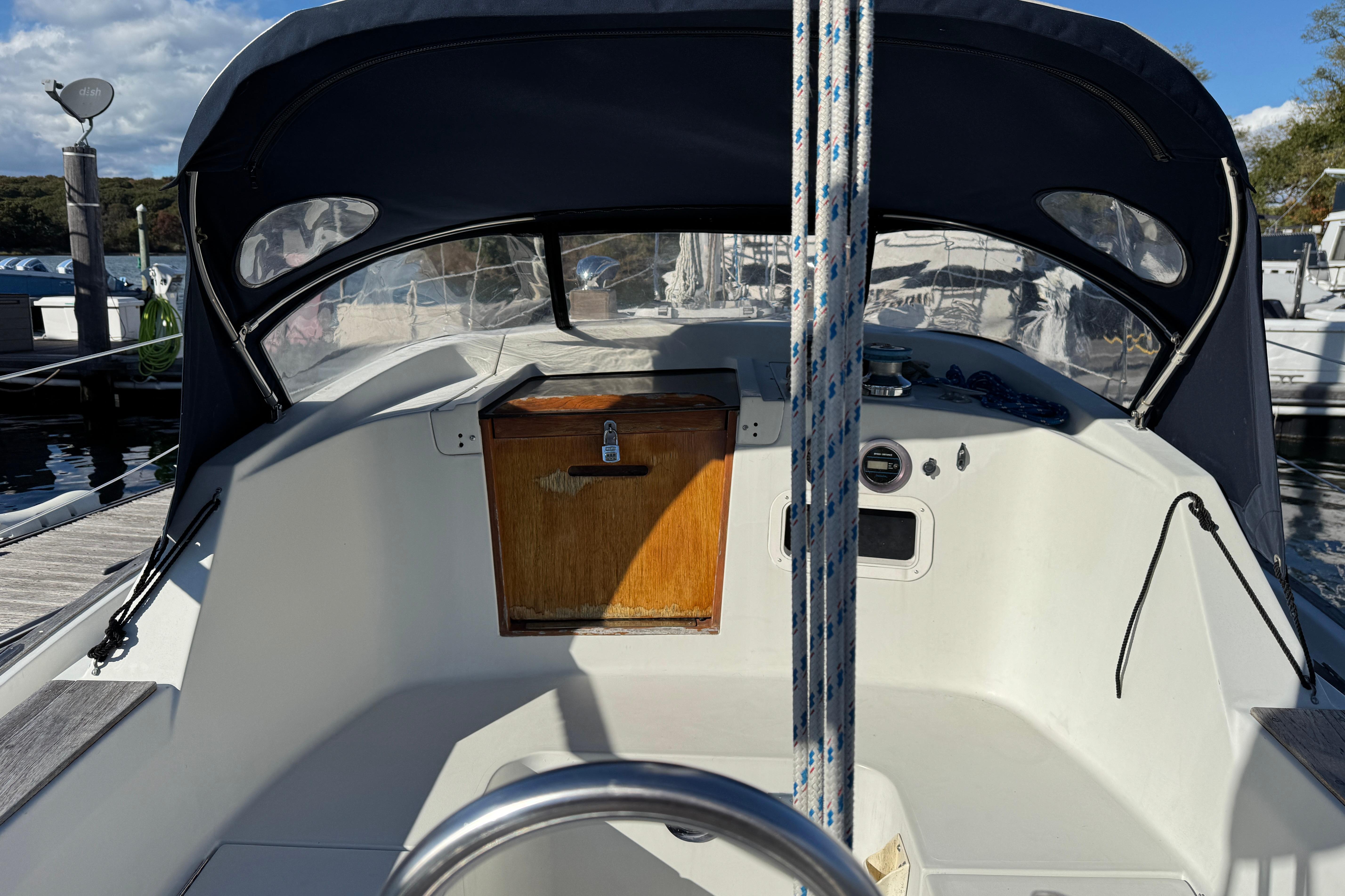 1984 C&C Landfall sailboat cockpit with wooden hatch and canopy at marina.