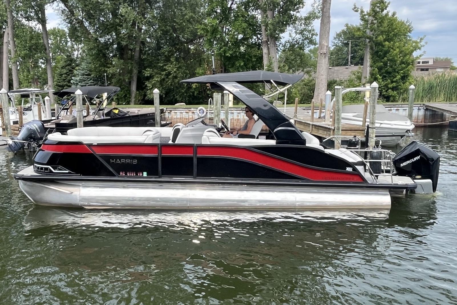 2024 Harris Grand Mariner 250 pontoon boat docked on a calm lake.