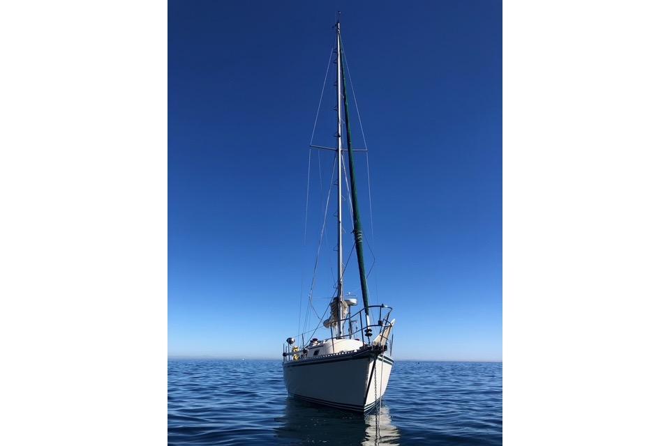 Sailboat on calm sea, 1991 Caliber 33, under clear blue sky.