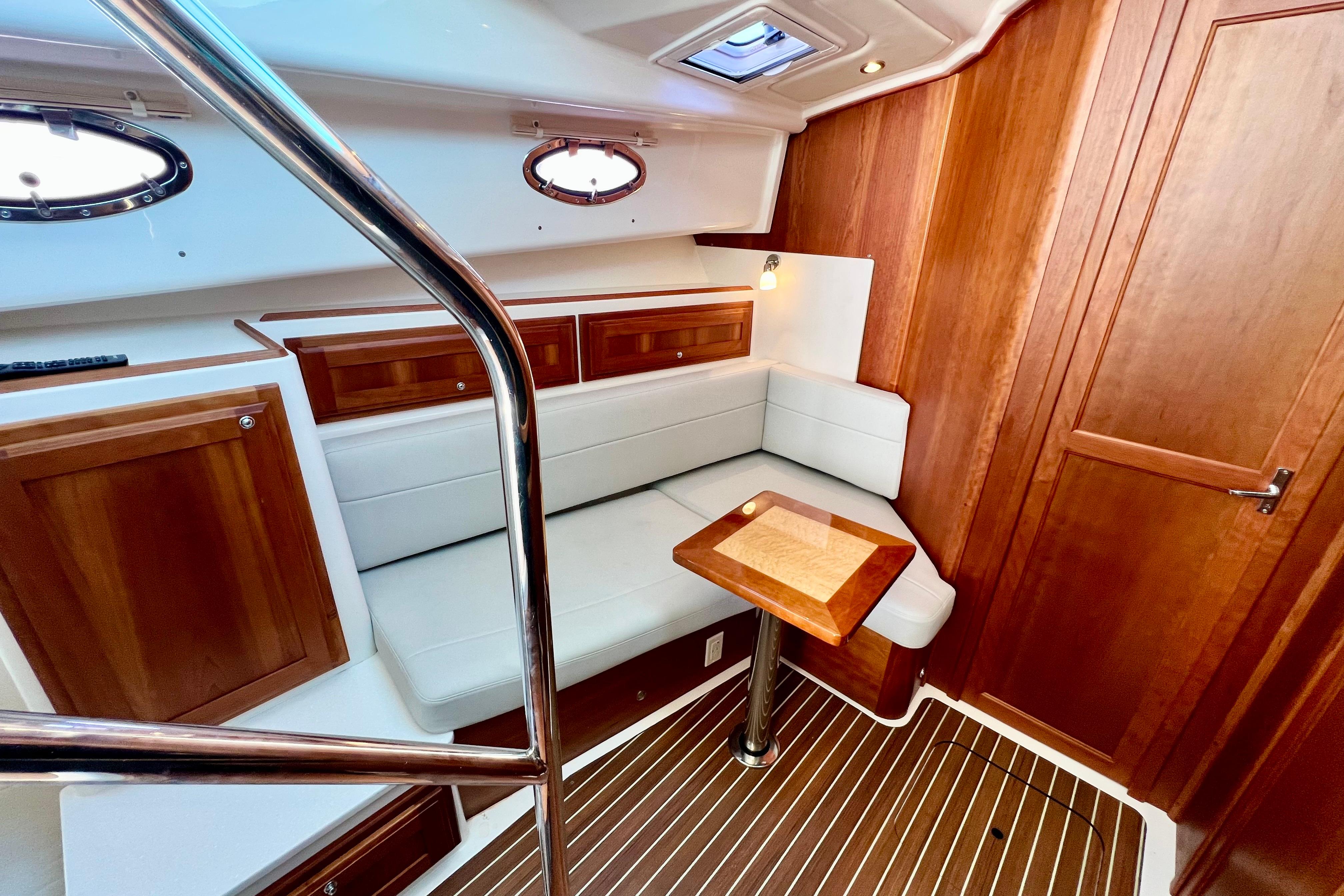 2021 Back Cove 390 interior with wood paneling, white seating, and a small table.