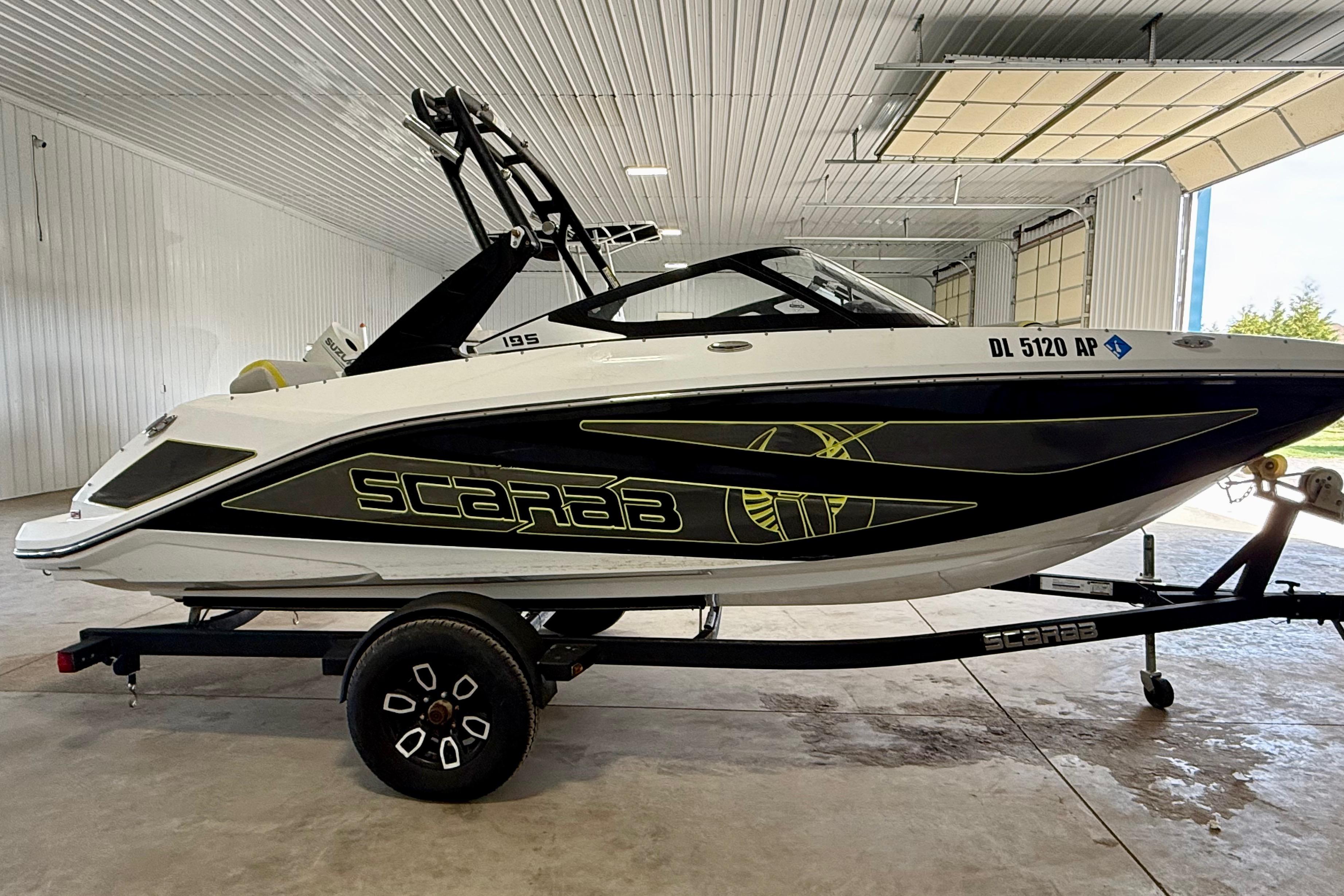 2023 Scarab 195 ID boat in a garage, featuring sleek black and white design.