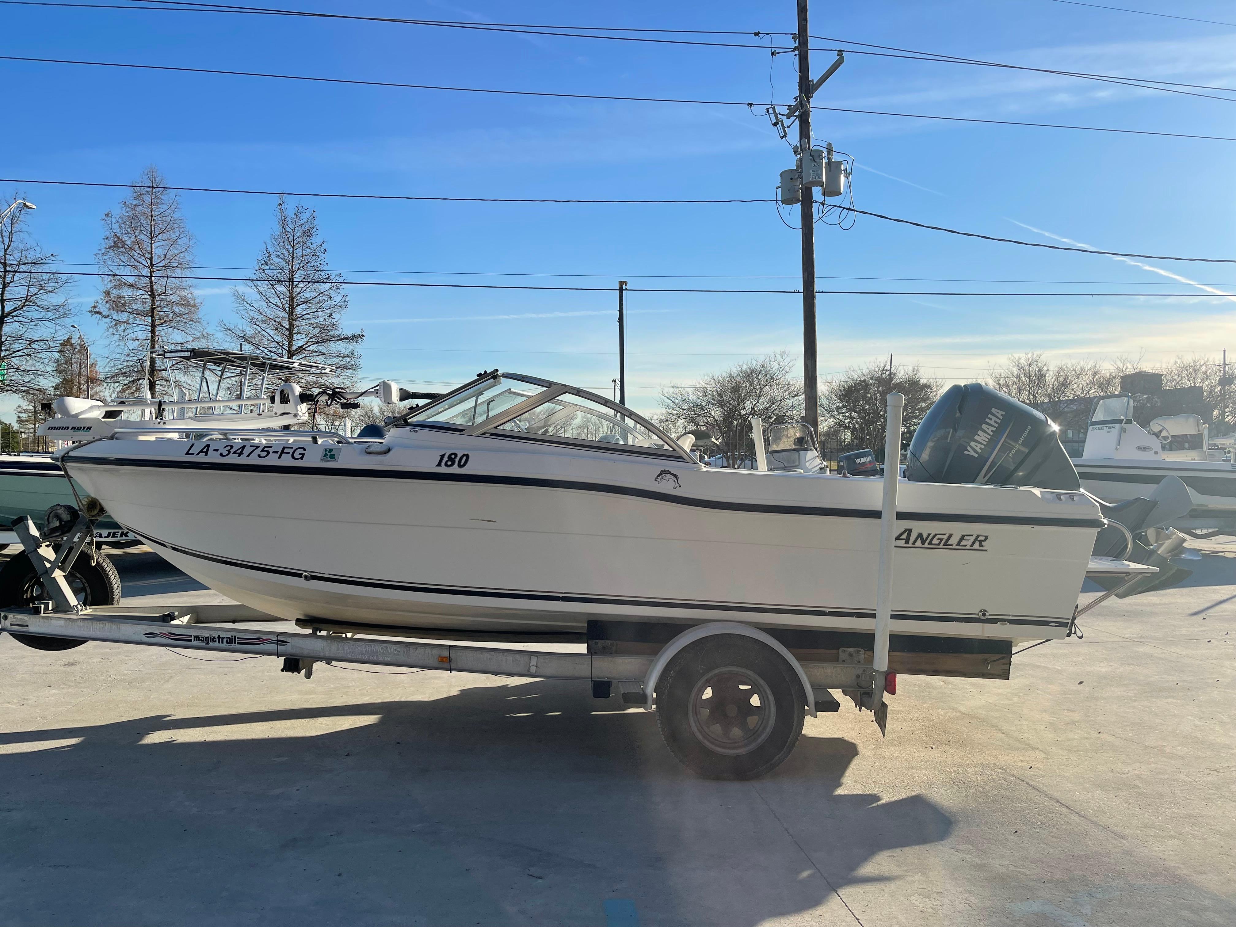 2002 Angler 18 DC boat on trailer, parked outdoors under clear blue sky.