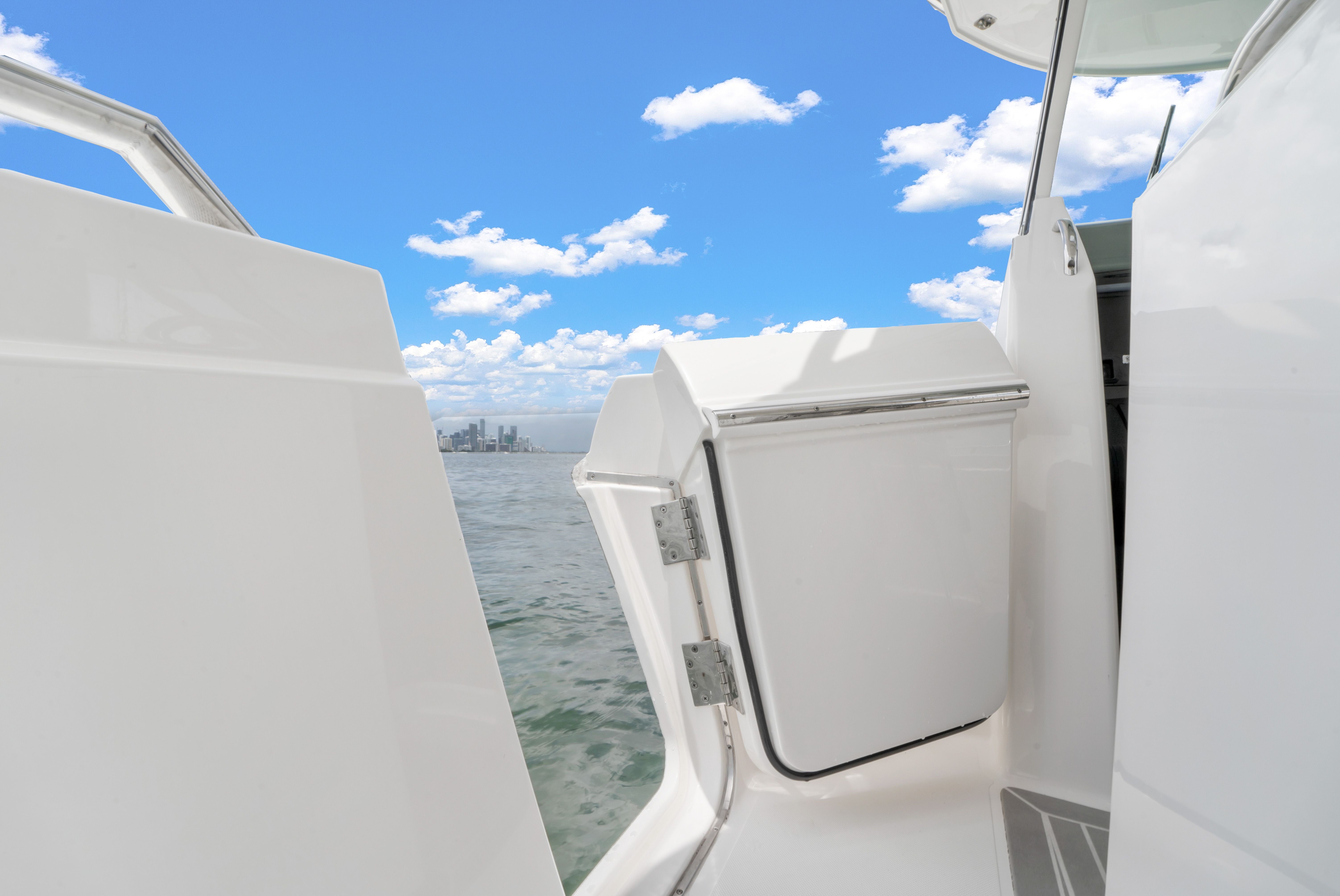 View from a boat overlooking the sea with a city skyline in the distance under a blue sky.
