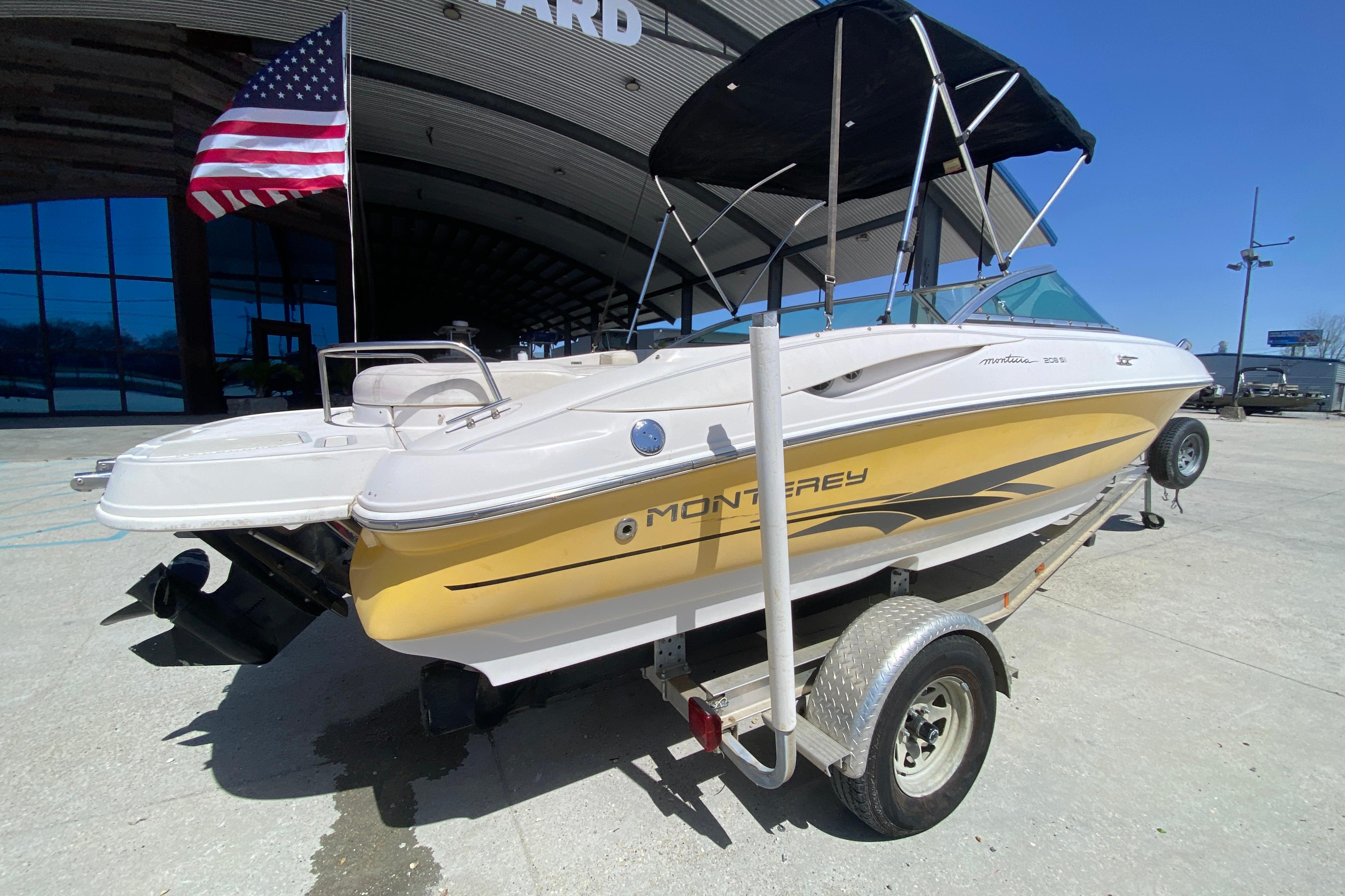 2003 Monterey 208SI Montura boat on trailer with American flag, parked outdoors.