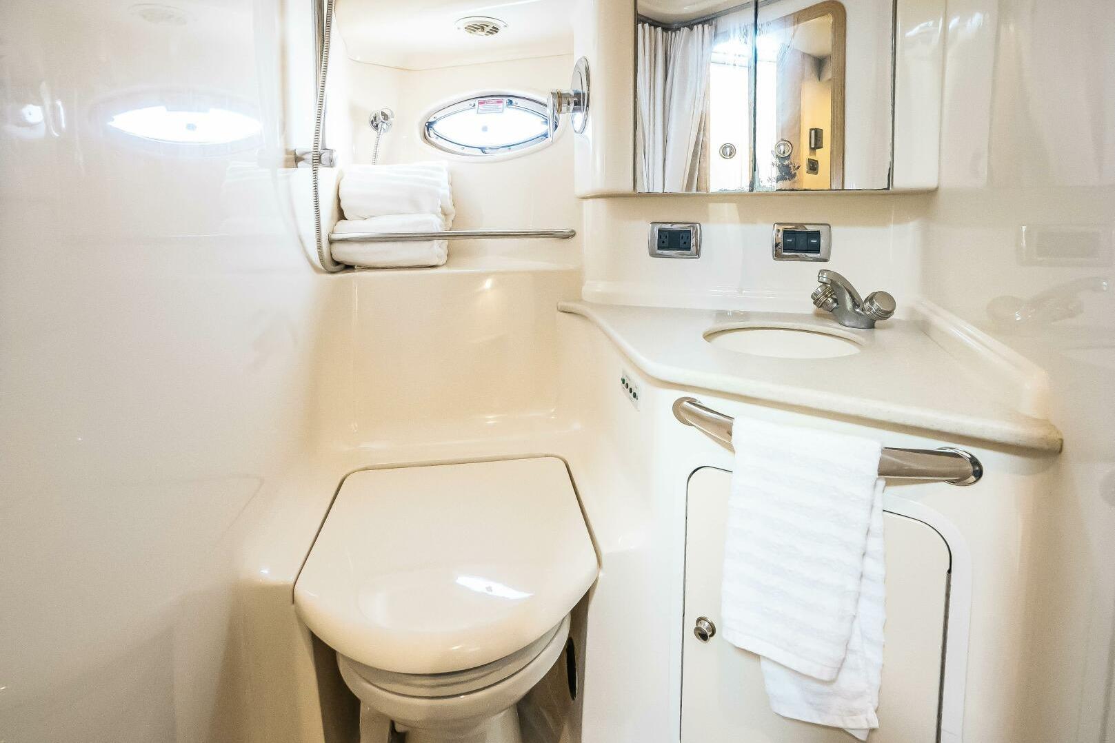 2003 Sea Ray Sundancer 460 yacht bathroom with toilet, sink, mirror, and towel.