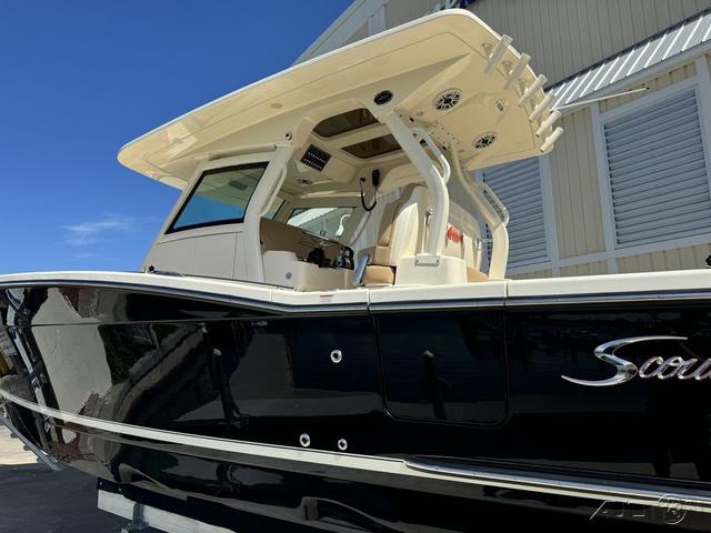 2022 Scout 330 LXF boat with black hull and beige interior, docked near a building.
