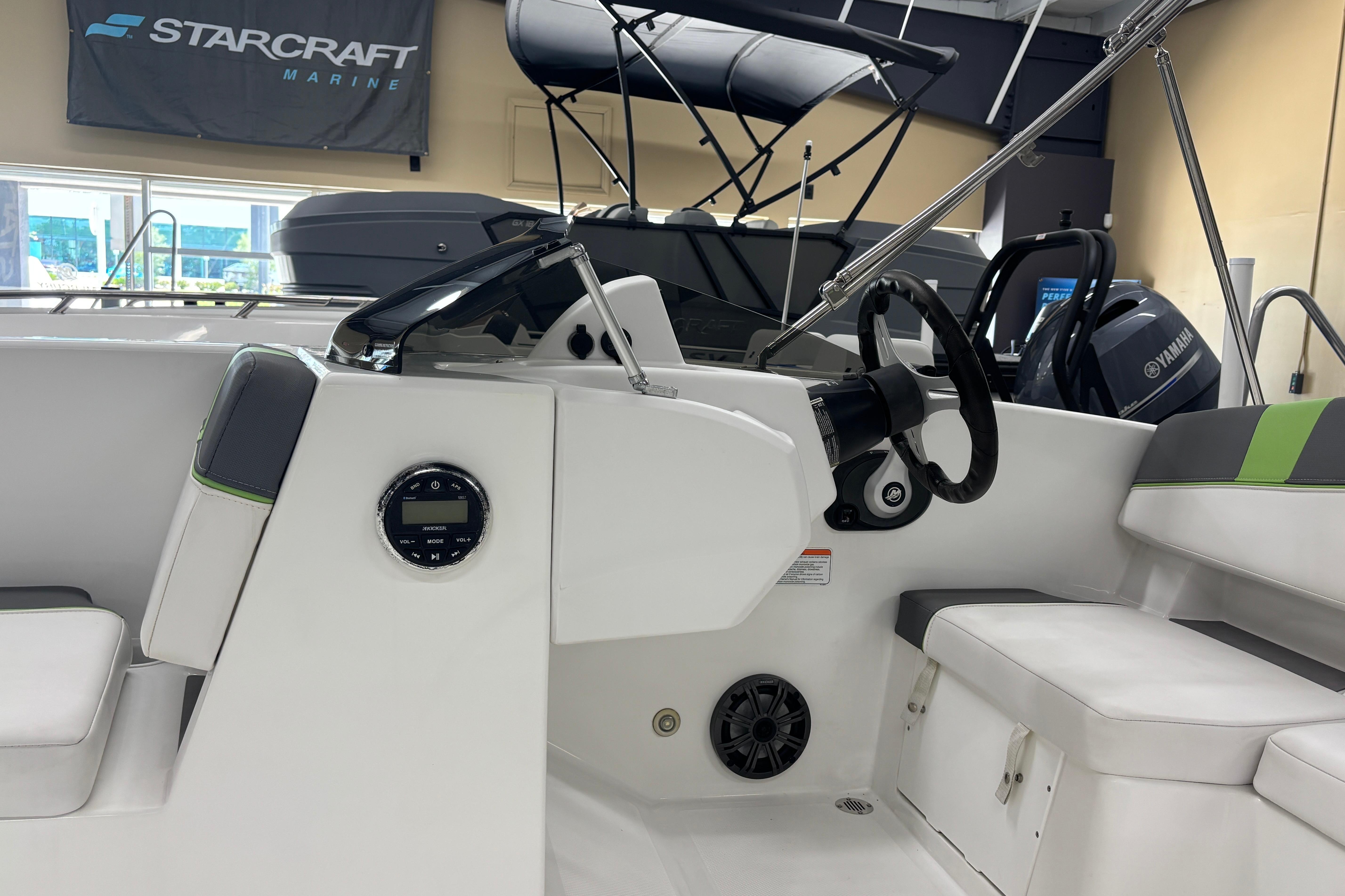 2024 Tahoe T18 boat interior with steering wheel and seating, displayed in a showroom.