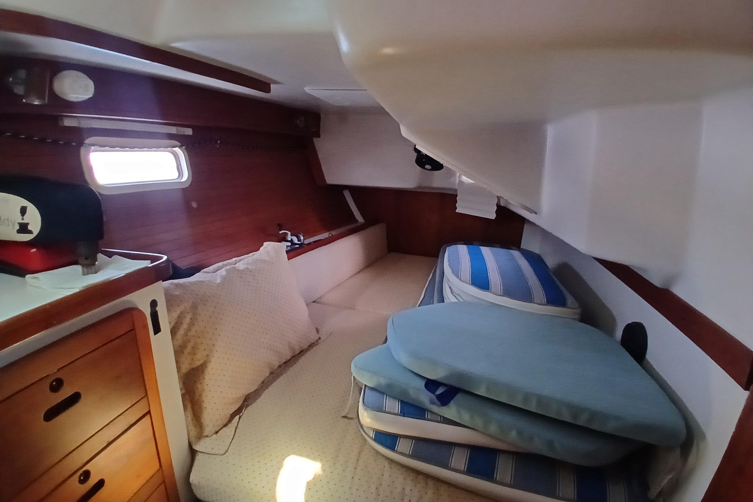 Cozy cabin interior of 1995 Catalina 42 MkII sailboat with cushions and wooden cabinetry.