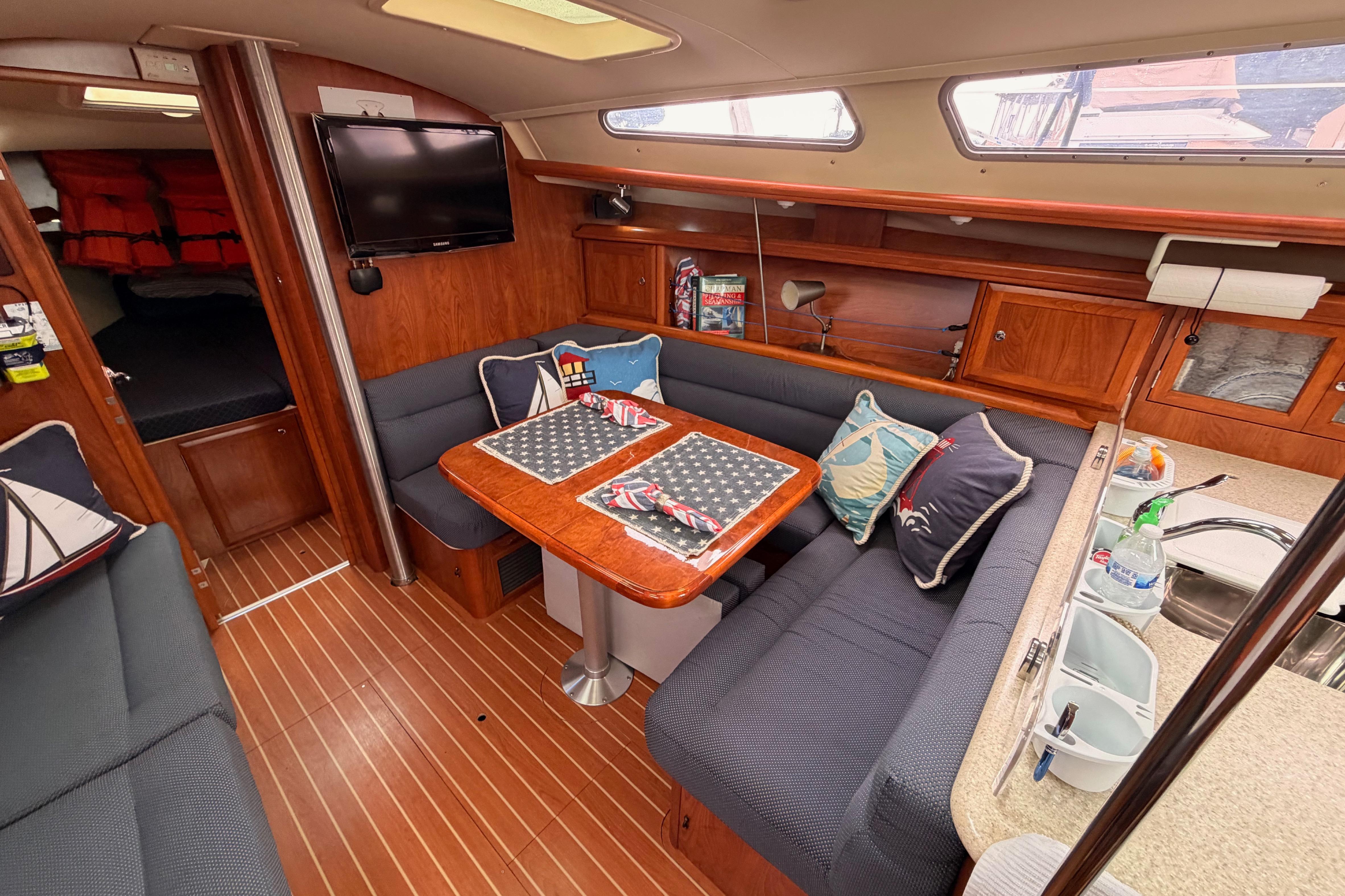 Interior of 2009 Hunter 38 sailboat with cozy dining area and nautical decor.