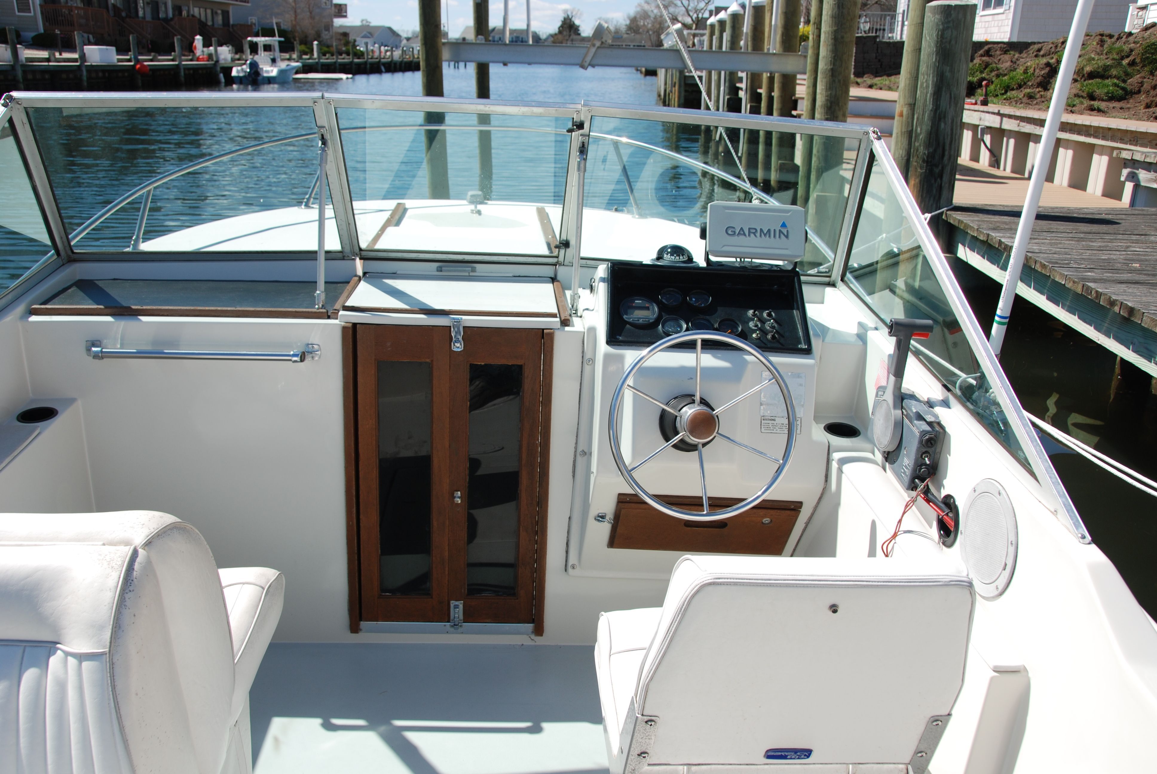 1987 Wellcraft V-20 Steplift with helm and Garmin device, docked by the water.