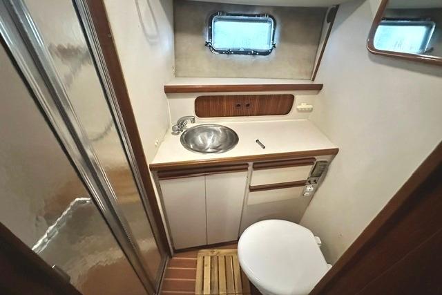 1989 Carver 32 Aft Cabin Motor Yacht bathroom with sink, toilet, and window.