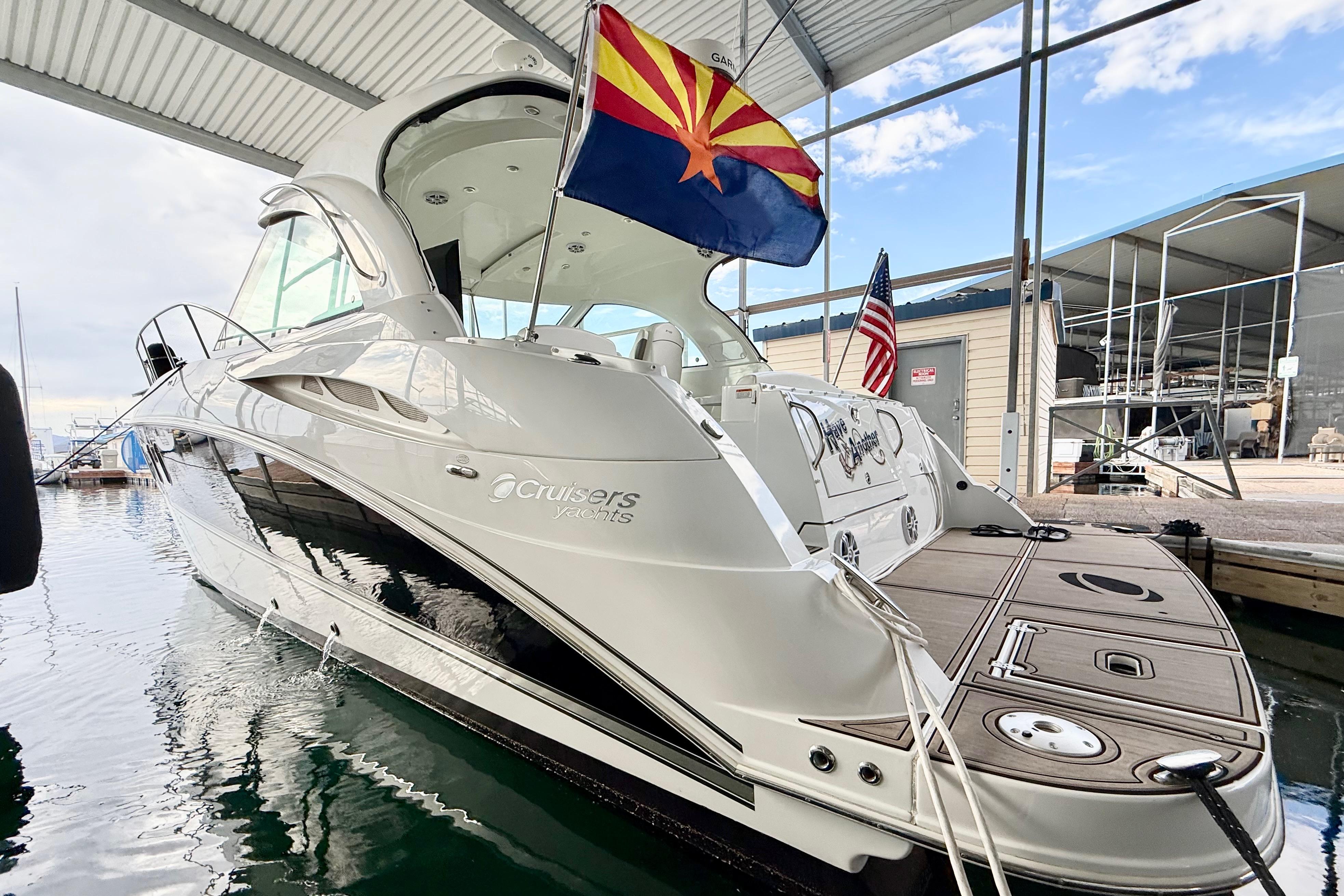 2011 Cruisers Yachts 390 Sports Coupe docked under a covered marina with flags displayed.