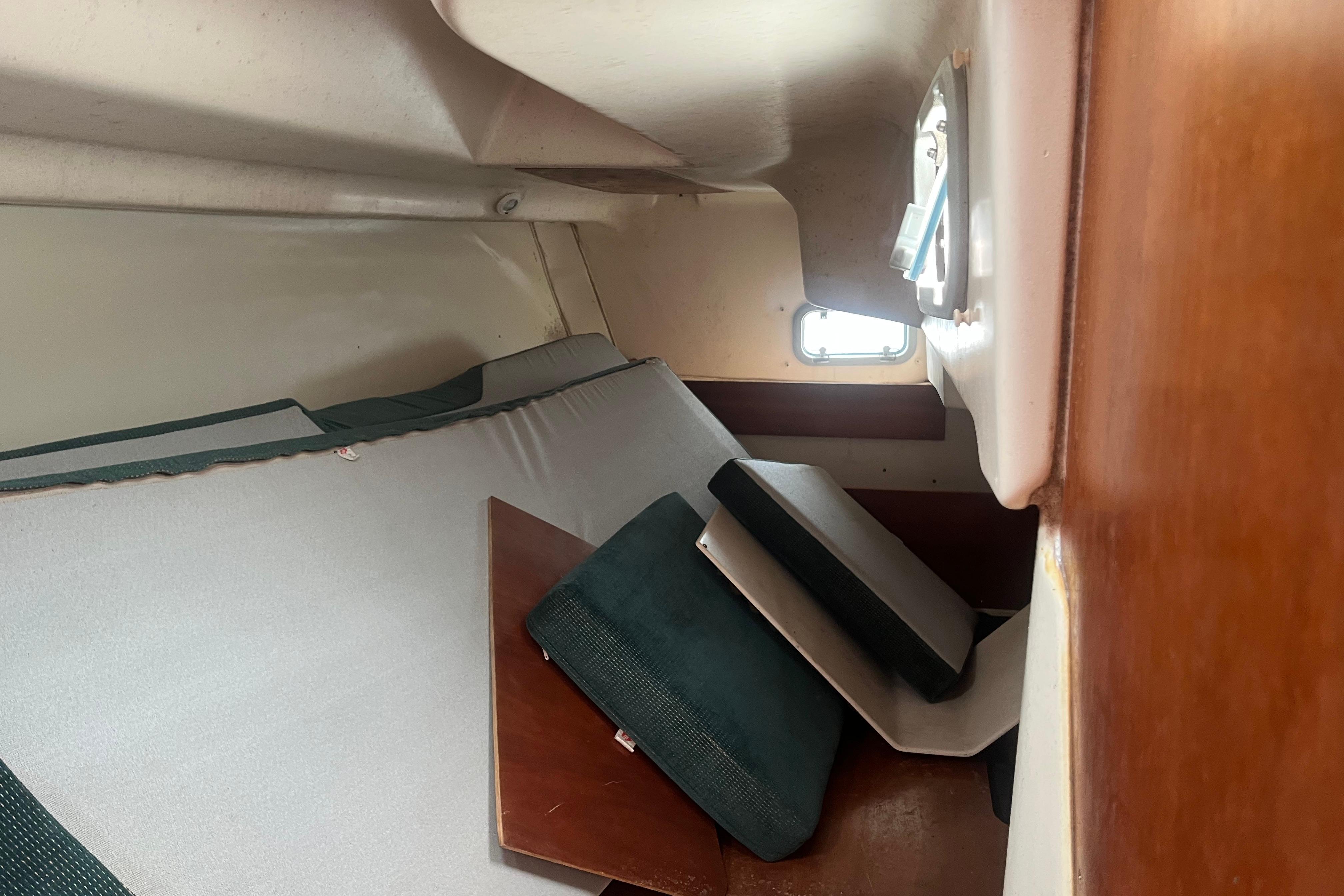 Interior cabin of 1999 Benneteau 321 Oceanis sailboat with cushions and window.