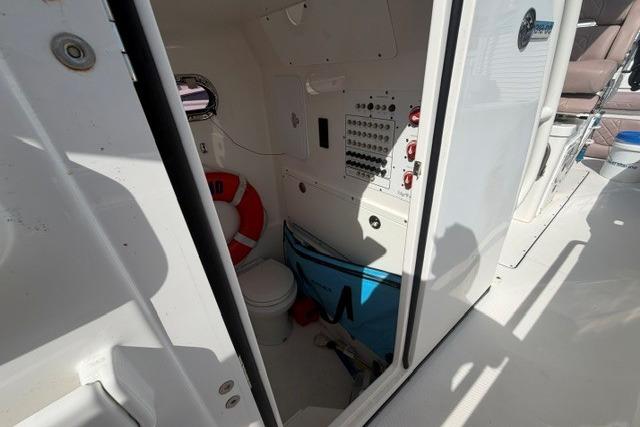 Interior of a 2014 Edgewater 318CC boat showing a compact restroom with safety equipment.