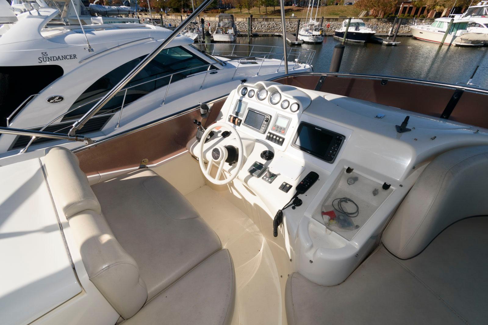 Azimut 50 Flybridge 2005 yacht helm with controls and seating in marina.