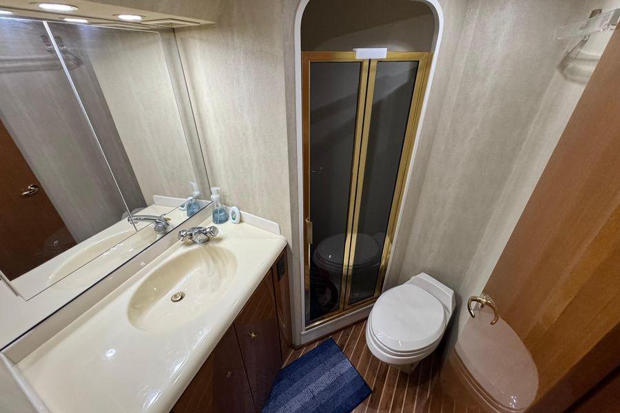 Bathroom interior of 2002 Viking 61 Enclosed Bridge yacht, featuring sink, toilet, and shower.