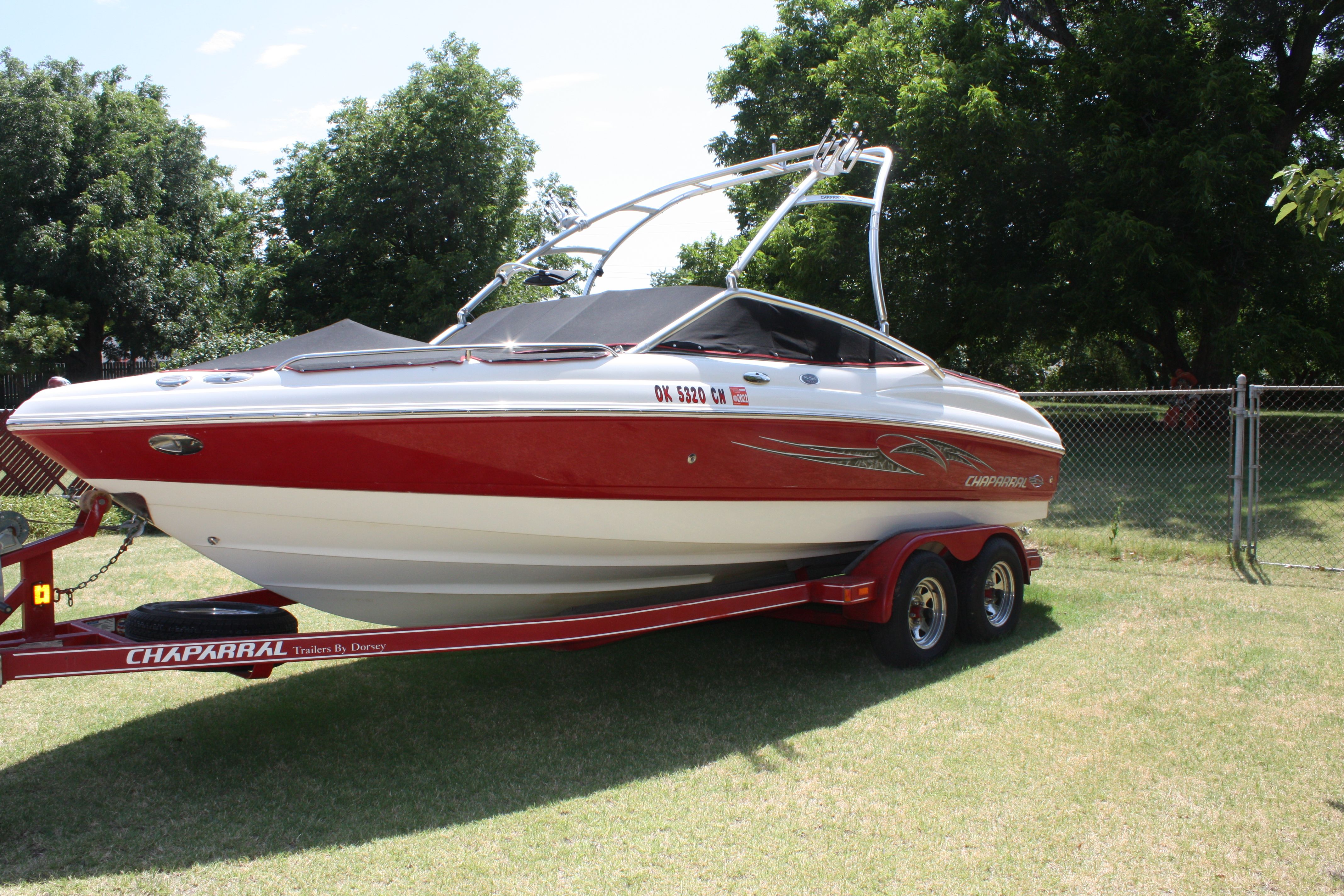 A red 2007 Chaparral 210 SSi boat on a trailer, parked on grass.
