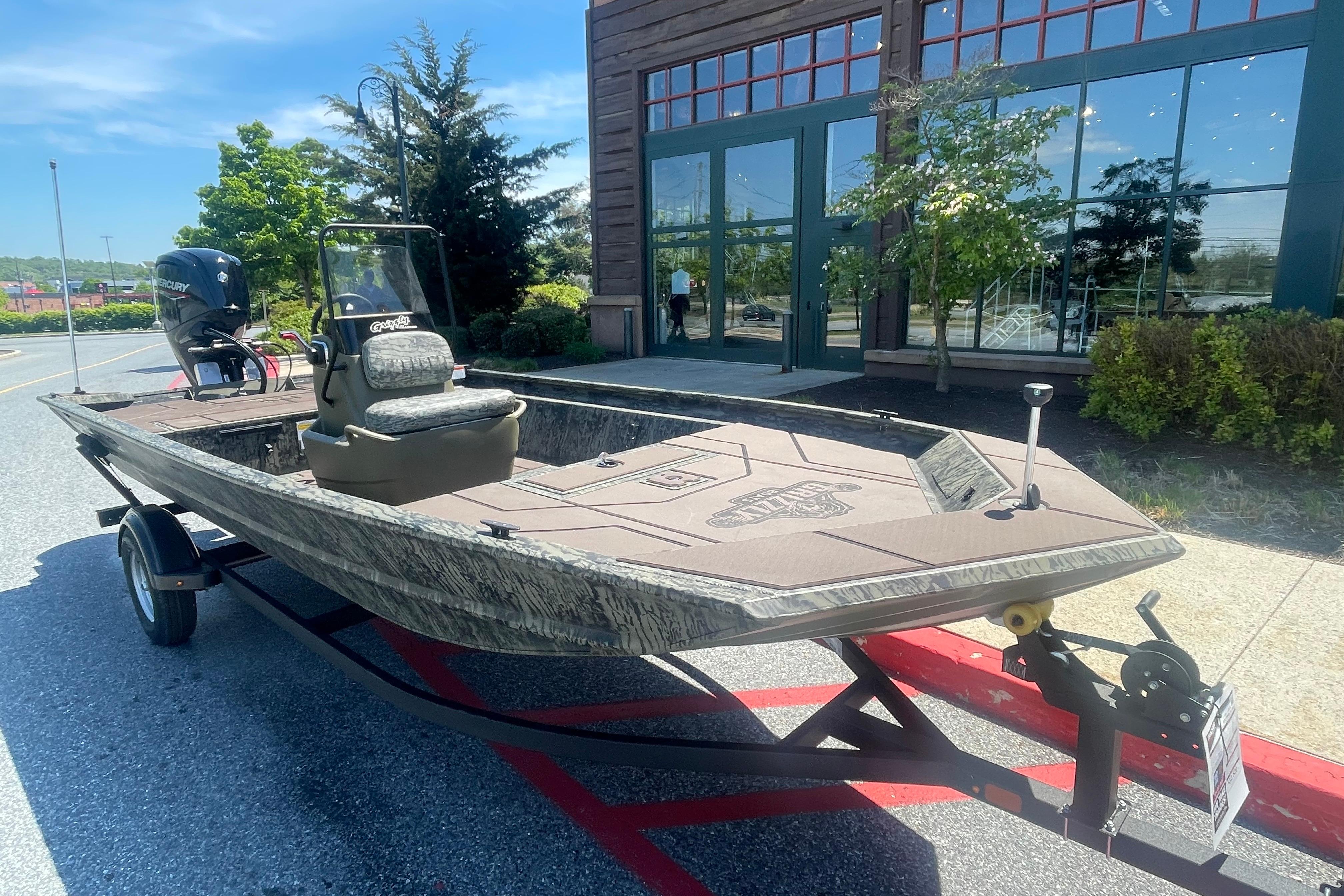 2026 Tracker Grizzly 1860 CC boat on trailer, parked outdoors near a building.