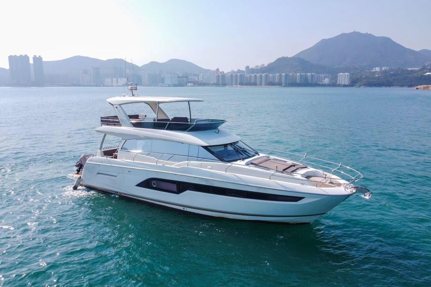 Luxurious 2019 Prestige 630 yacht cruising on serene waters with scenic mountain backdrop.