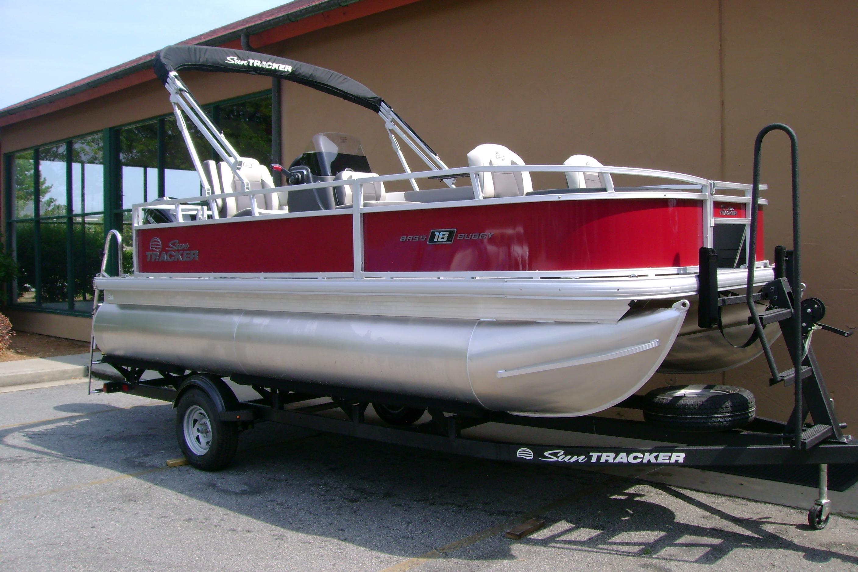 2026 Sun Tracker Bass Buggy 18 DLX pontoon boat on trailer, parked outdoors.