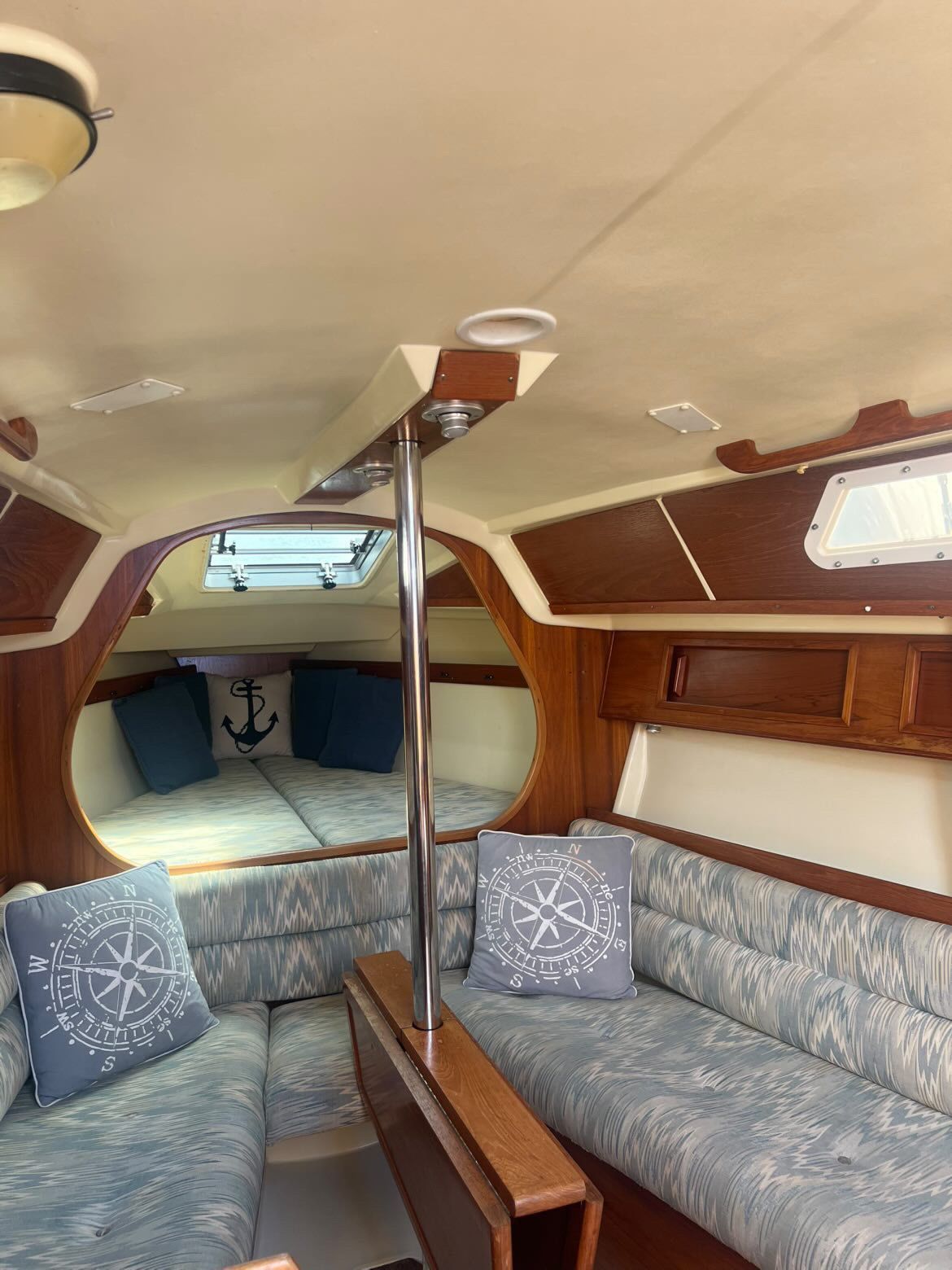Interior of a 1988 Pearson 28 sailboat with cozy seating and nautical-themed cushions.