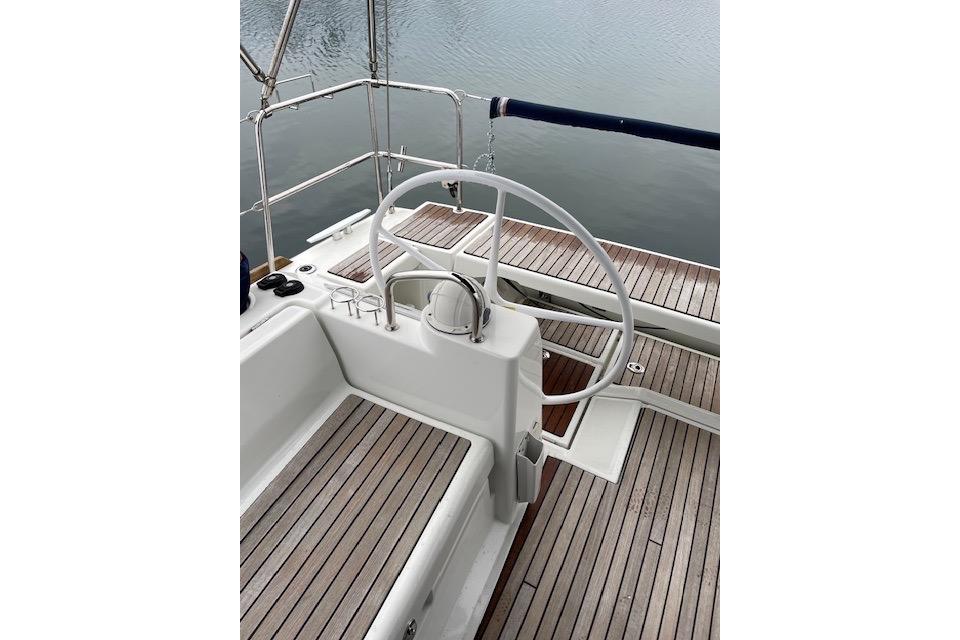 Cockpit of 2018 Beneteau Oceanis 45 sailboat with wooden deck and steering wheel.