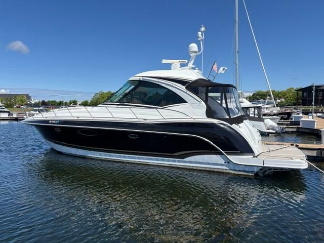 A sleek motor yacht with a black hull and white superstructure, docked at a marina.