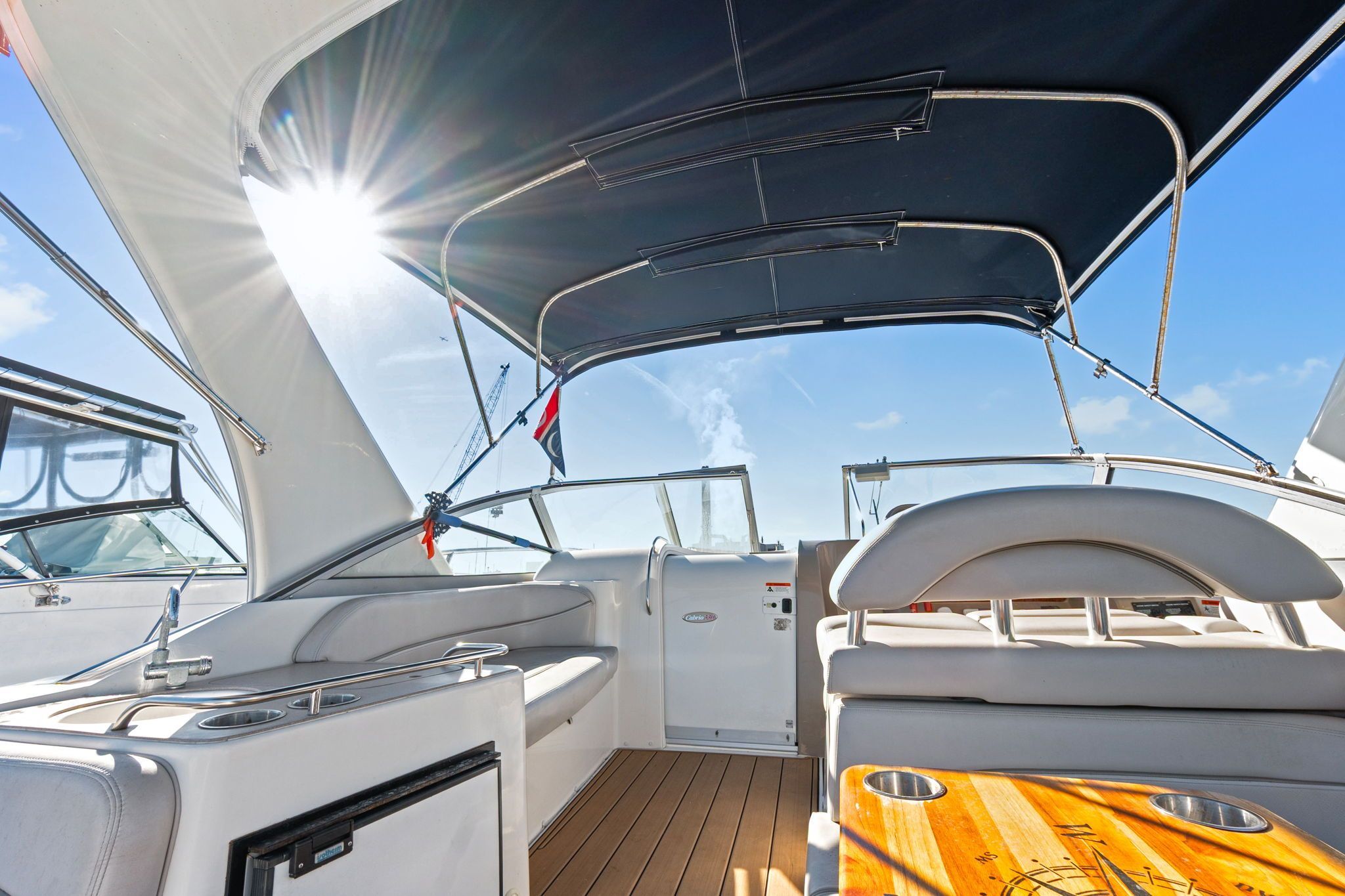 The image shows the cockpit of a 2007 Larson Cabrio 330 with sunshade and wooden table.