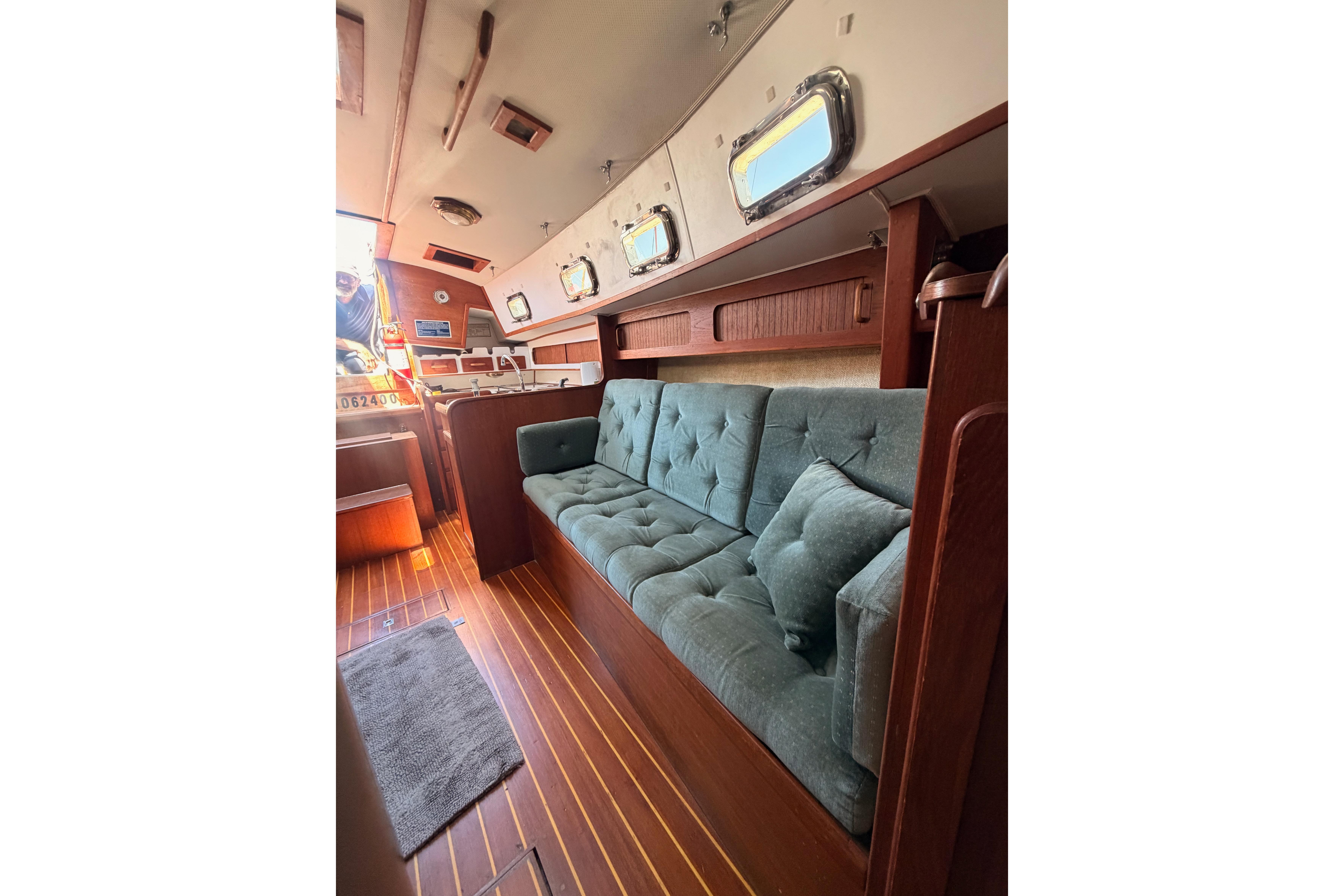Interior of 1991 Caliber 33 sailboat with teal sofa and wooden accents.