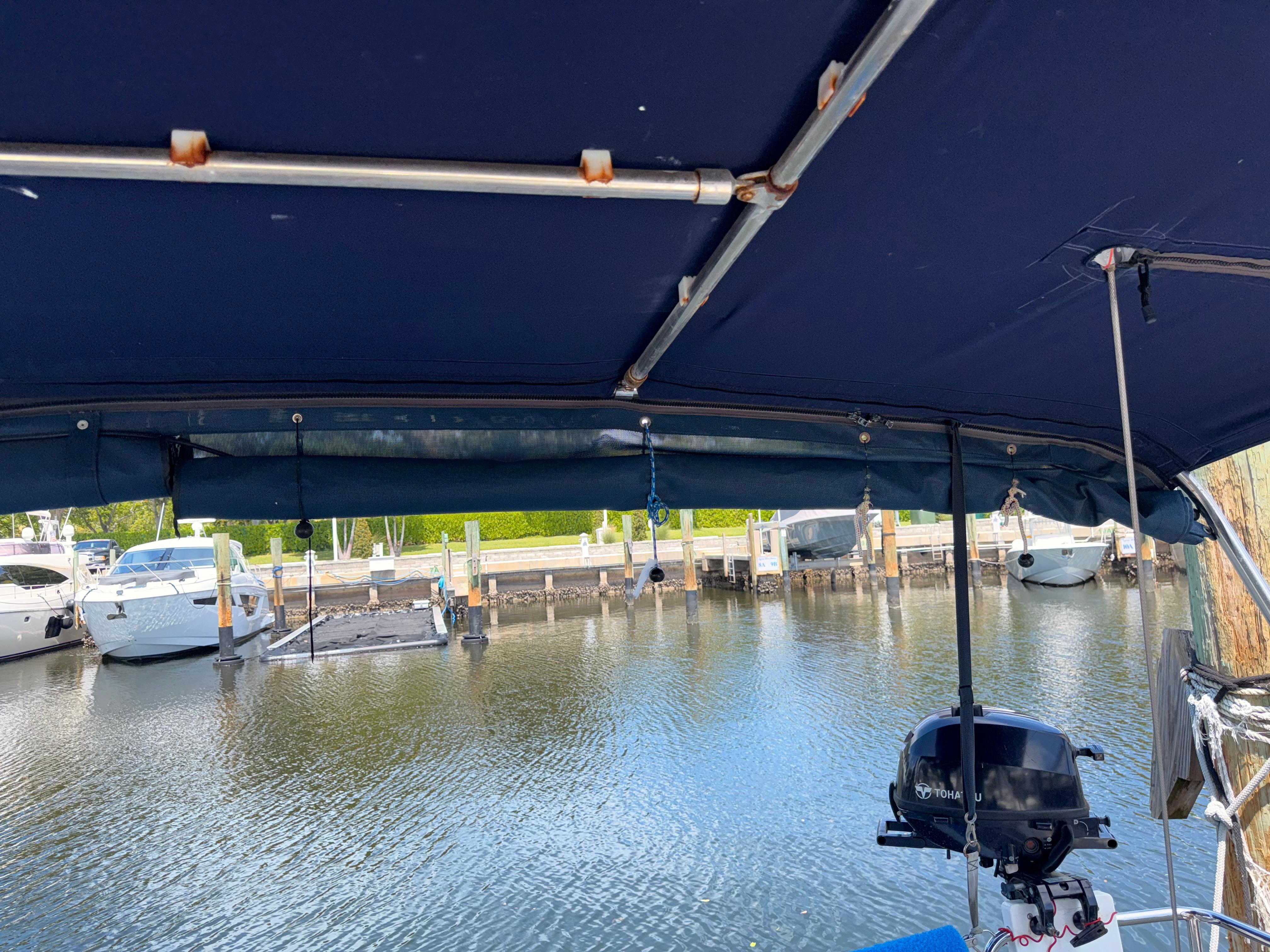 Beneteau Oceanis 45 (2016) docked, view from under blue canopy, marina background.