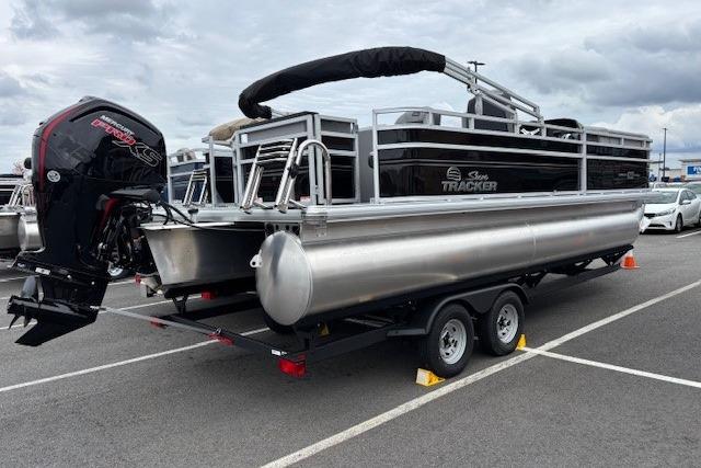 2026 Sun Tracker SportFish 22 DLX pontoon boat on trailer in parking lot.