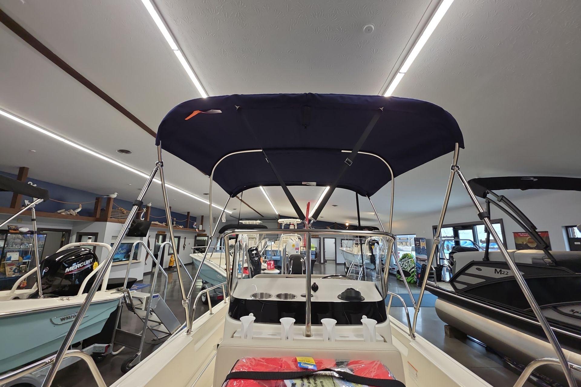 2026 Boston Whaler 150 Montauk boat with canopy in showroom display.