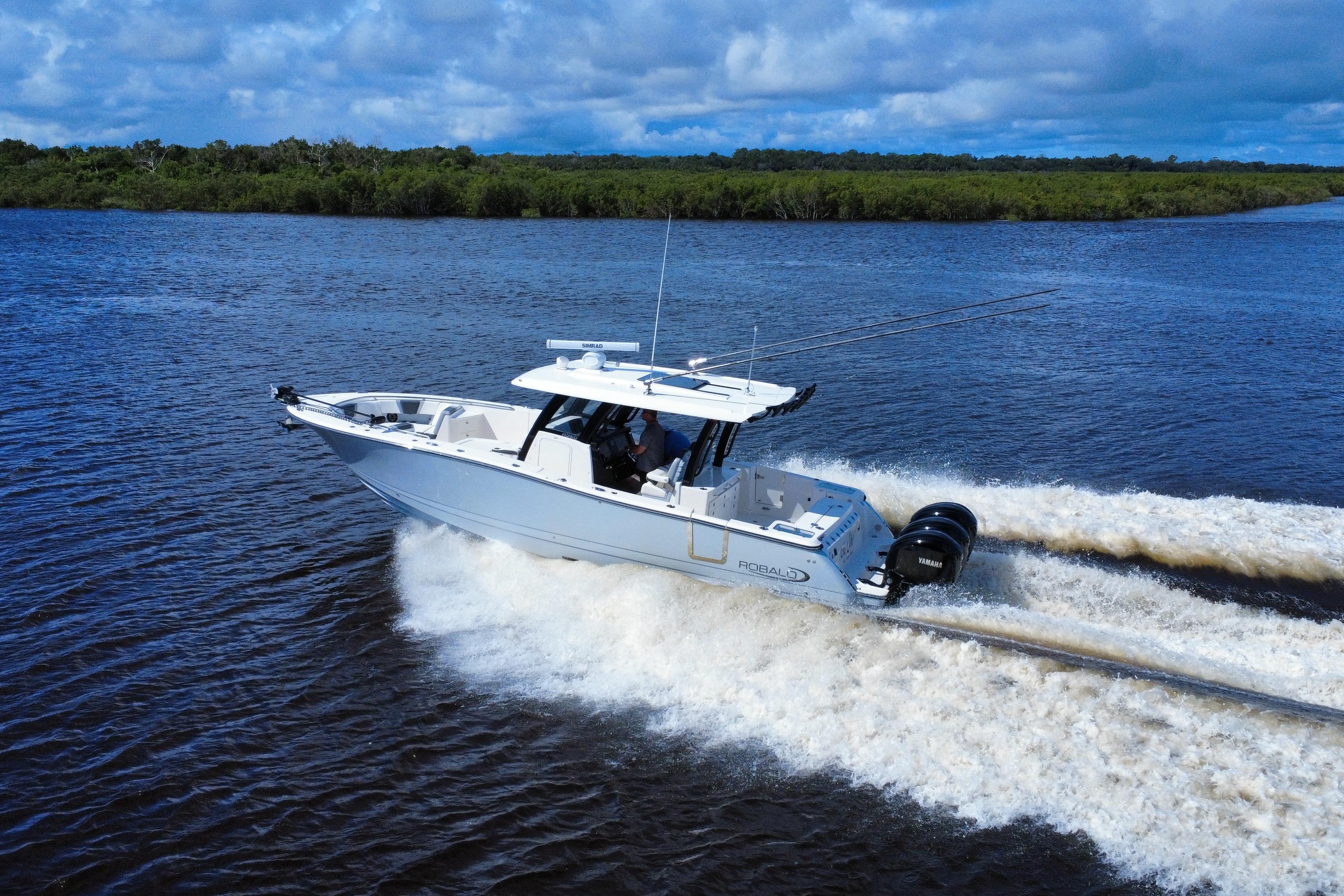 2022 Robalo R360 Center Console boat cruising on a river under a cloudy sky.