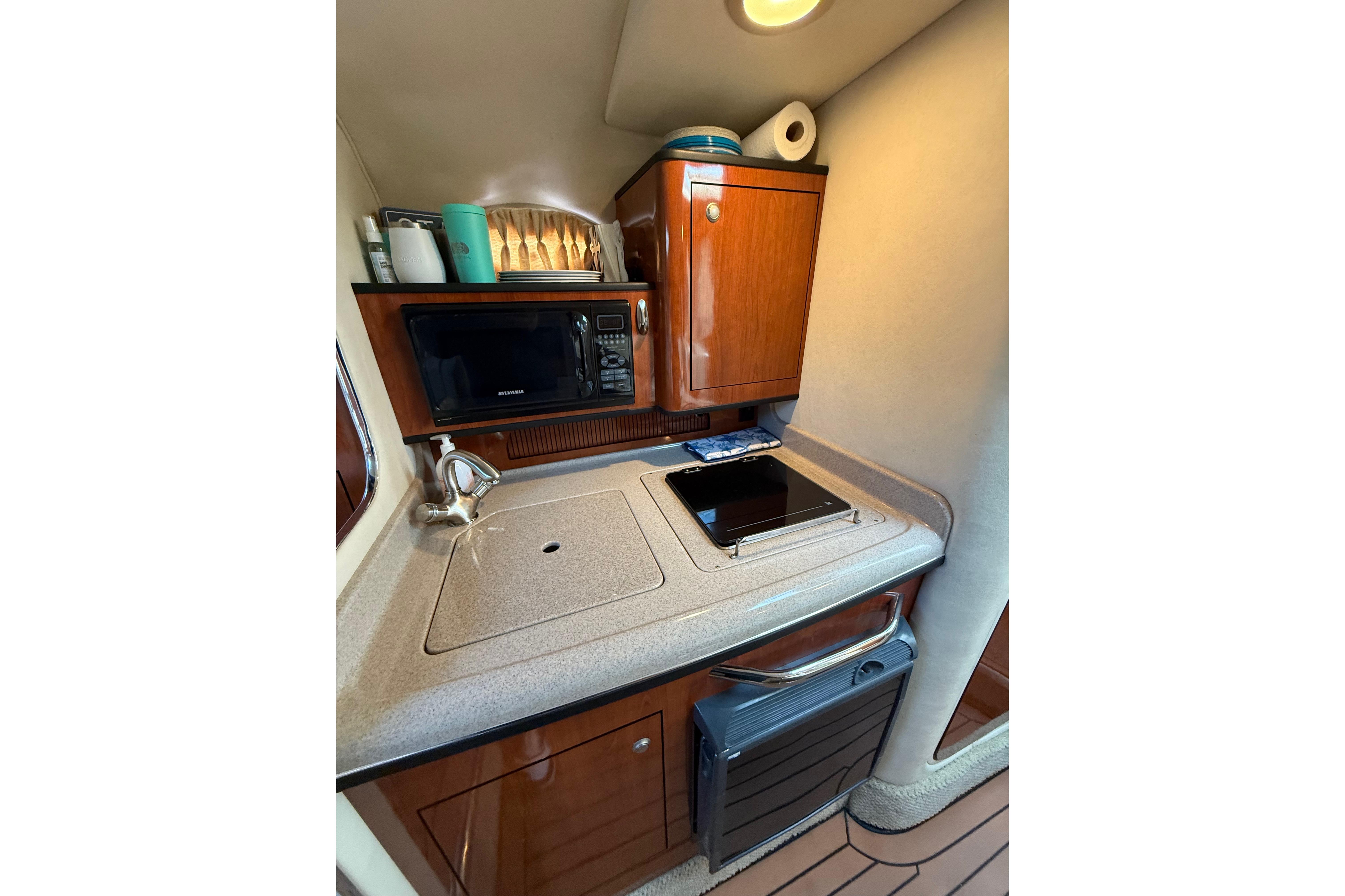 2007 Sea Ray 280 Cuddy Cabin kitchenette with sink, microwave, and storage cabinets.