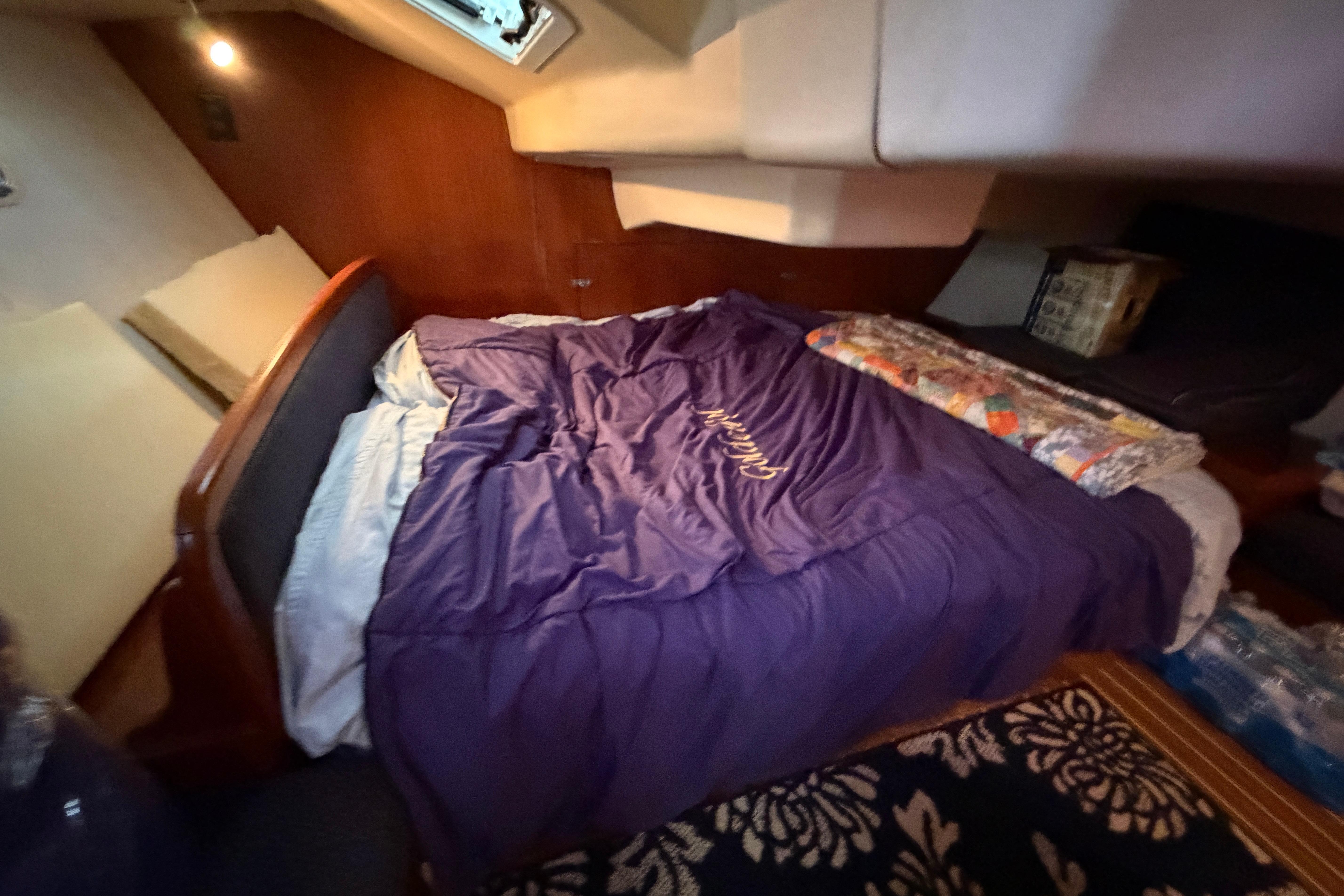 Cozy cabin interior of 2005 Hunter 38 sailboat with bed and soft lighting.