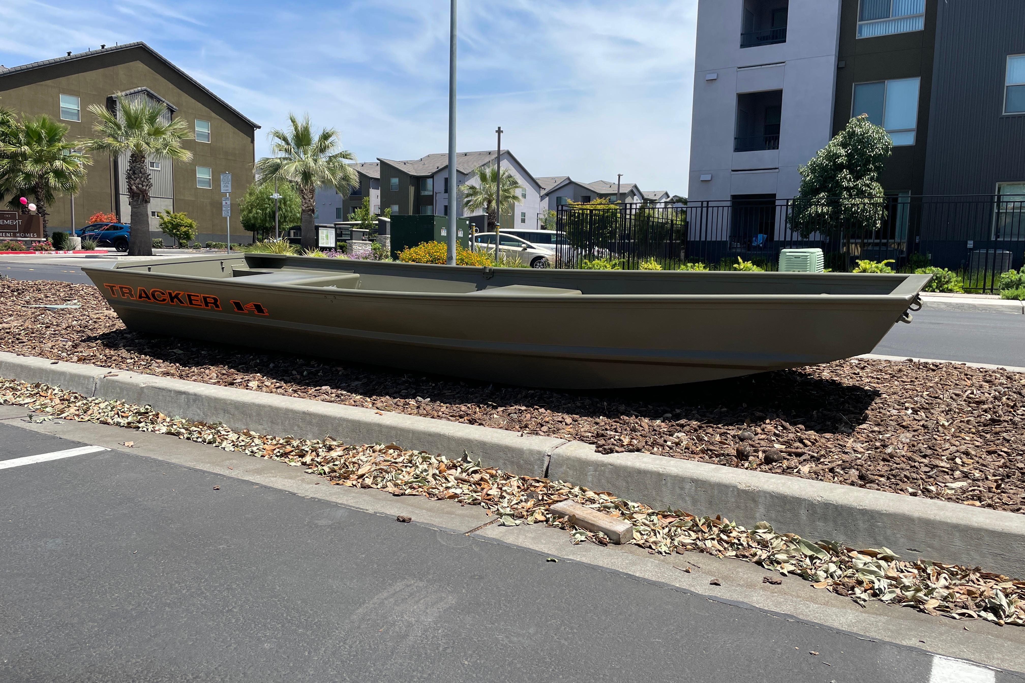 2026 Tracker Grizzly 14 Jon boat displayed outdoors near residential buildings.
