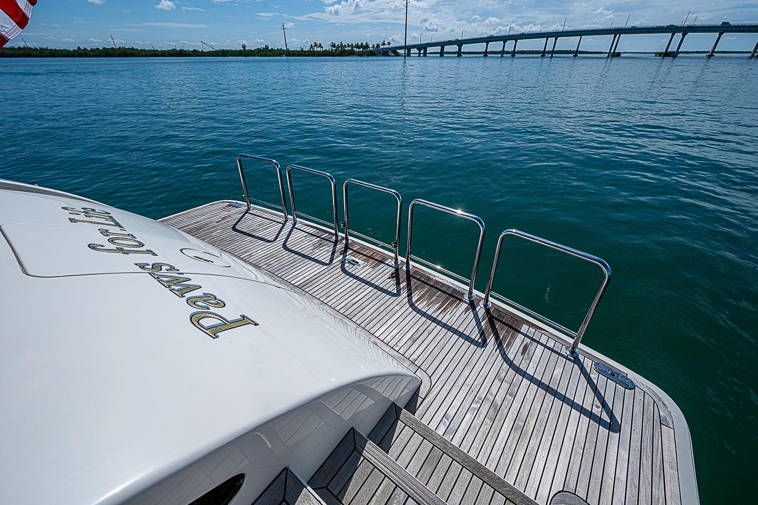 Stern view of 2014 Marlow 80 Explorer yacht with wooden deck and ocean backdrop.