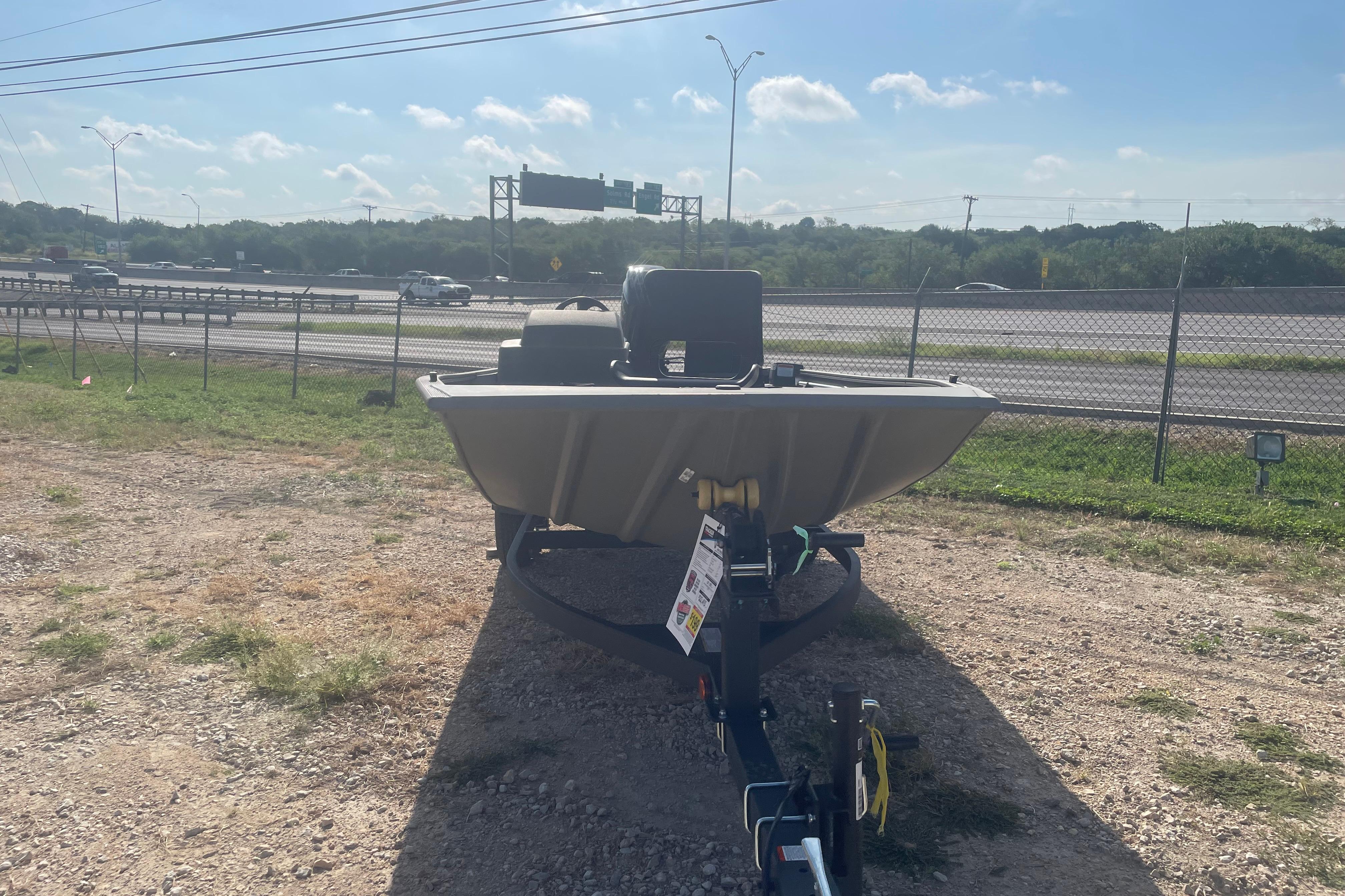2026 Tracker Grizzly 1754 SC boat on trailer near highway, sunny day.