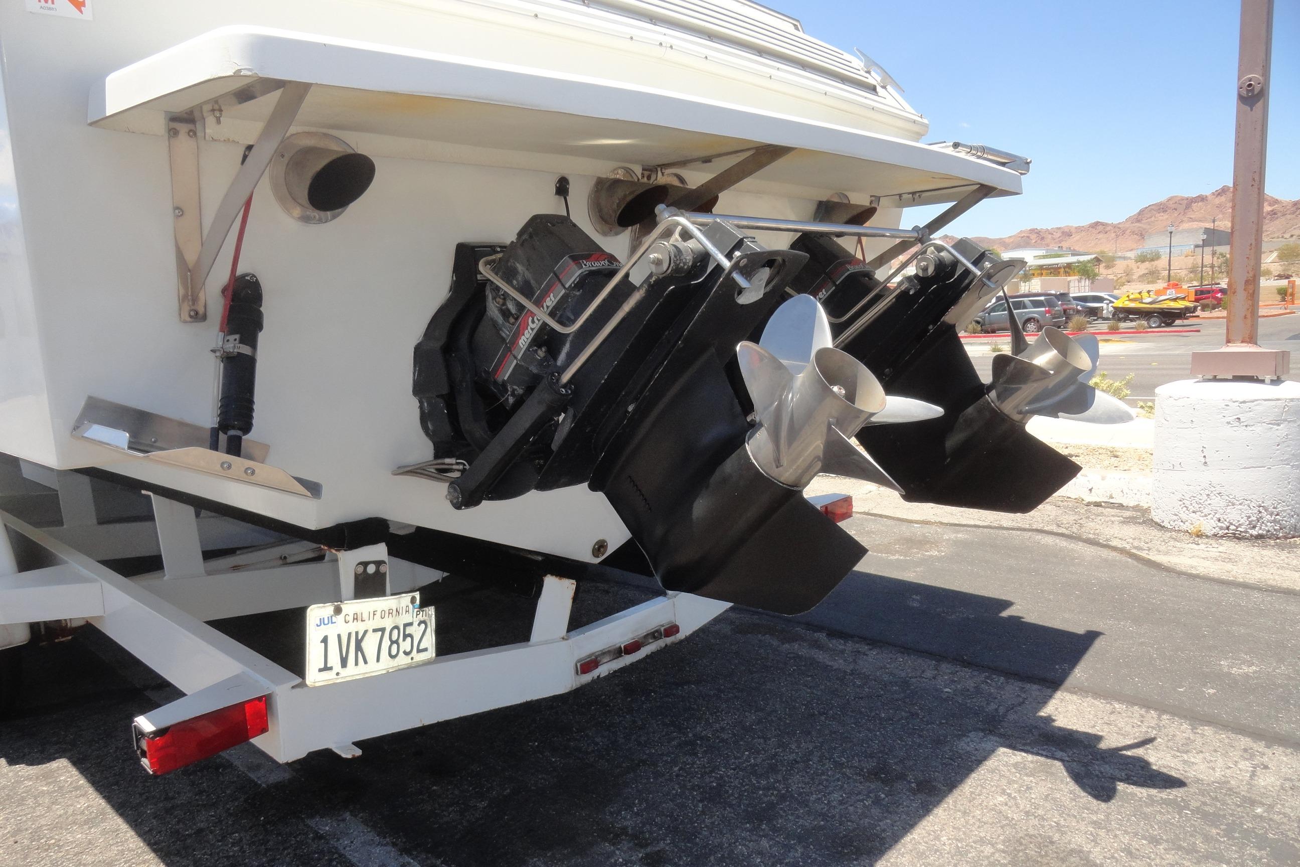 1988 Wellcraft 34 Scarab boat with dual propellers on a trailer in a parking lot.