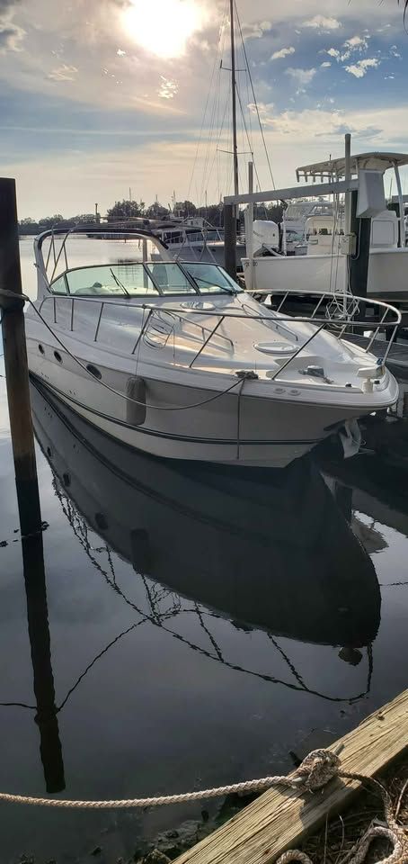 A 2002 Wellcraft 3300 Martinique docked in calm waters, reflecting the sky.