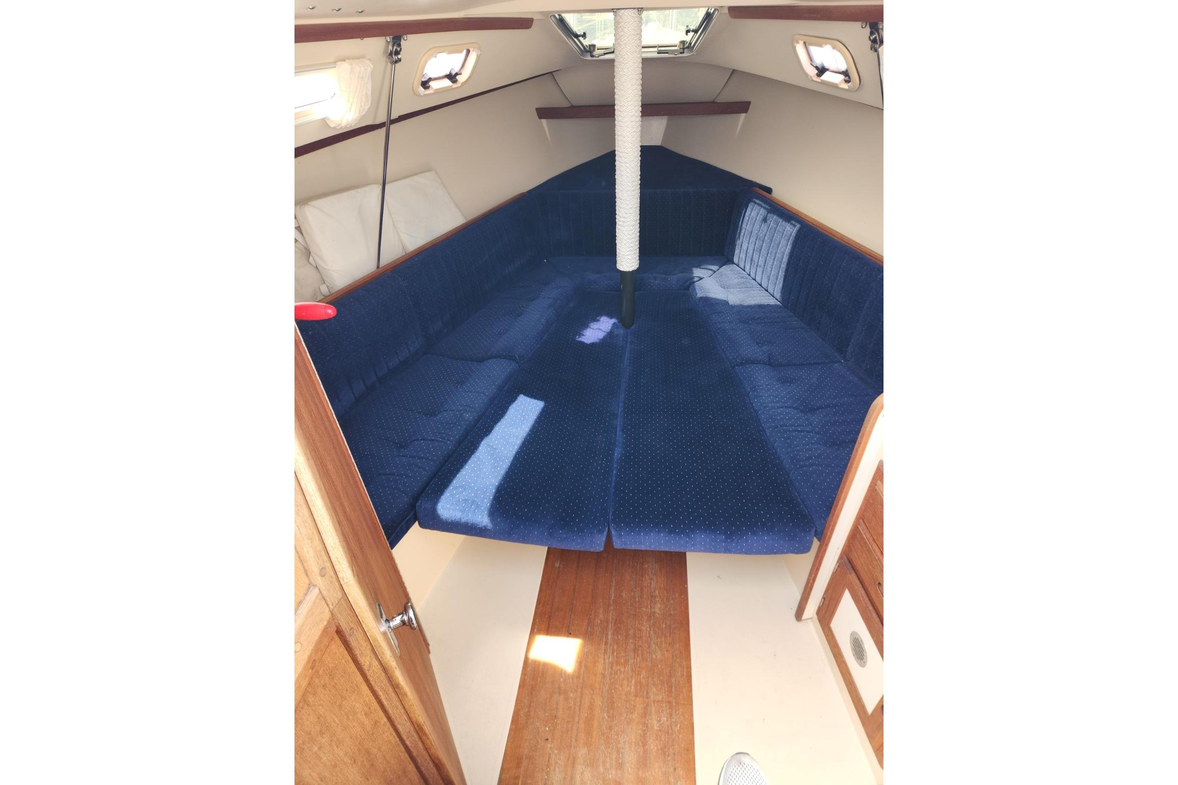 Interior of a 1990 Catalina Capri sailboat with blue cushioned seating.
