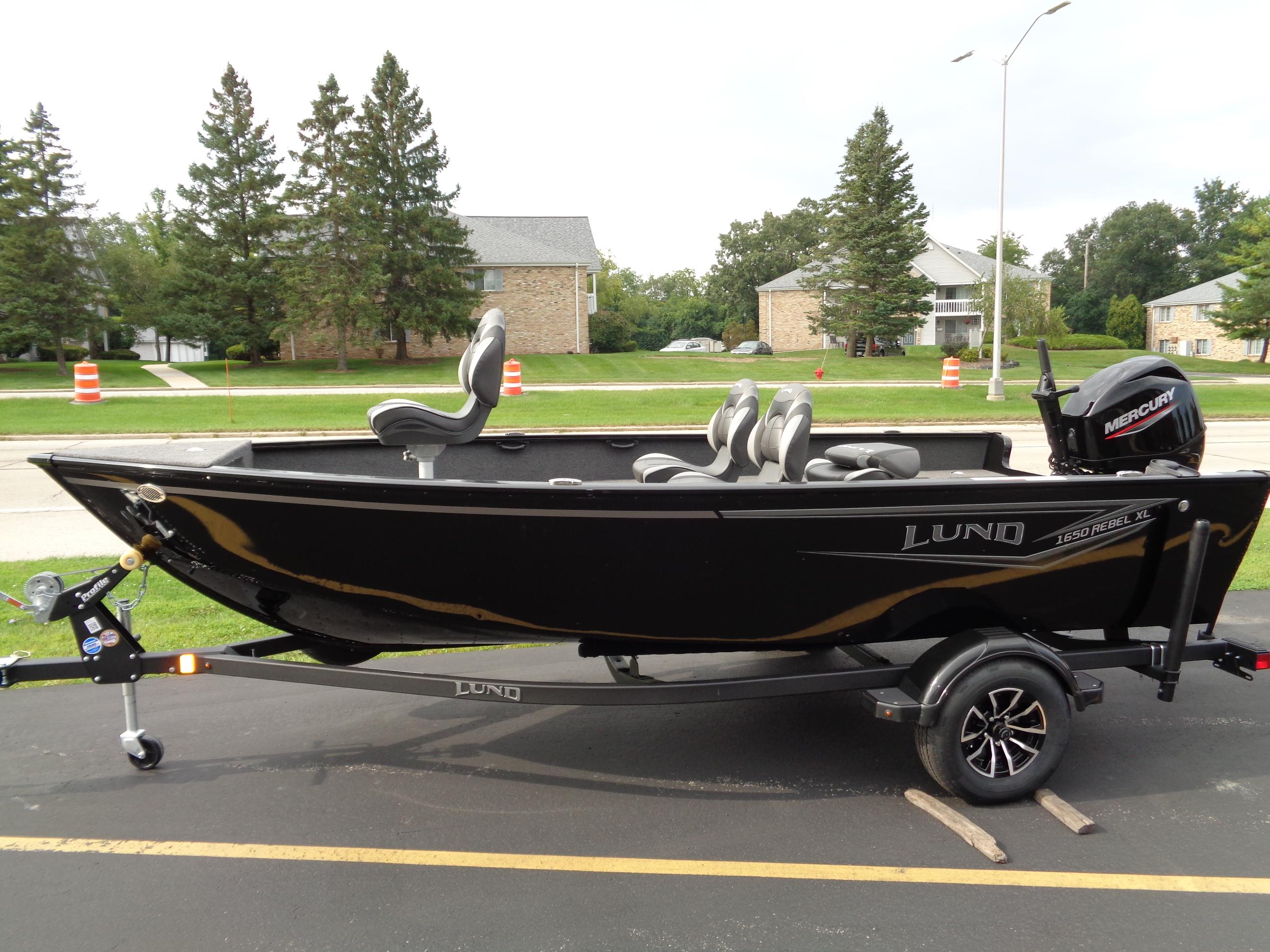 2025 Lund 1650 Rebel XL Tiller boat on trailer, black exterior, parked outdoors.
