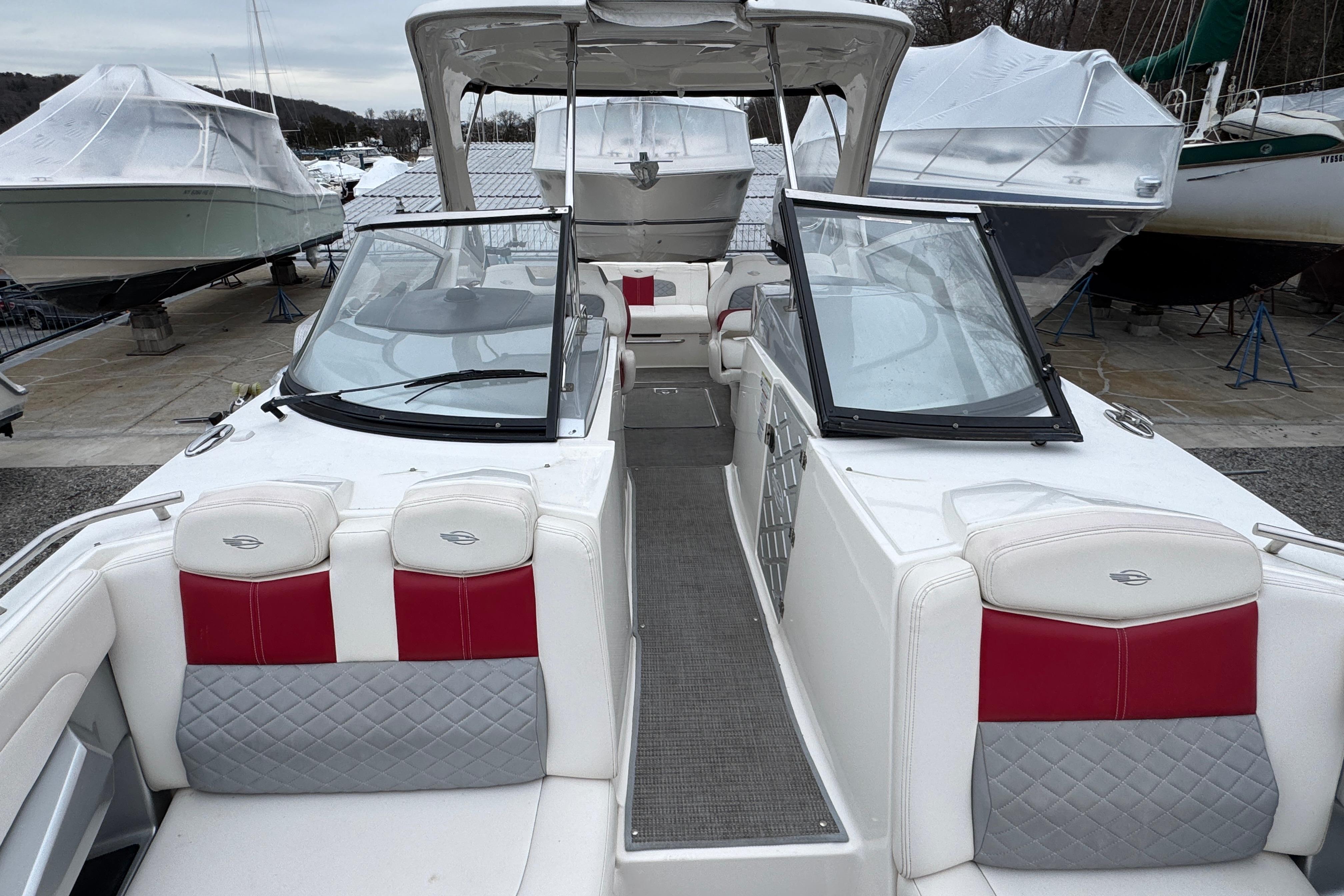 2012 Chaparral 327 SSX boat with white and red interior, docked among covered boats.
