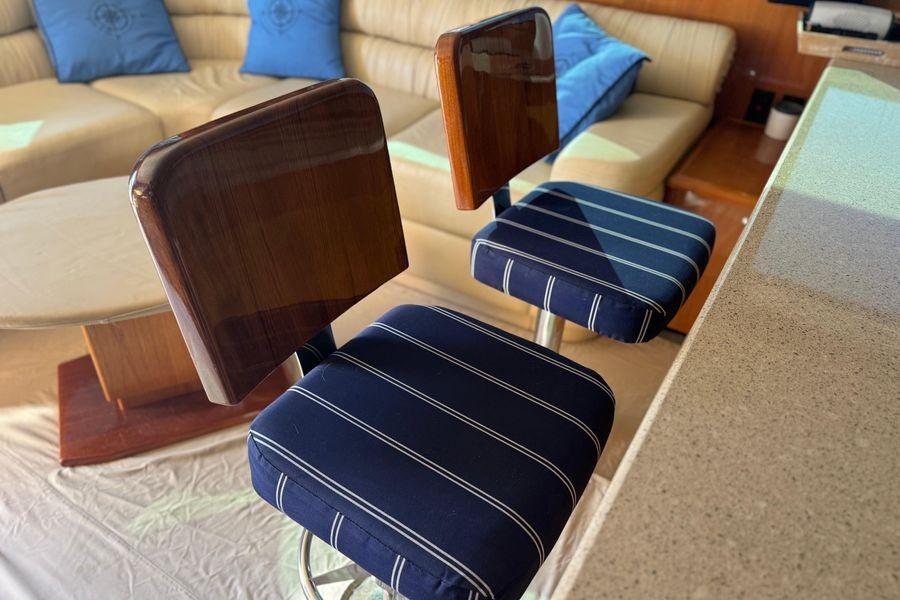 Interior of 2002 Viking 61 Enclosed Bridge with striped bar stools and beige seating.