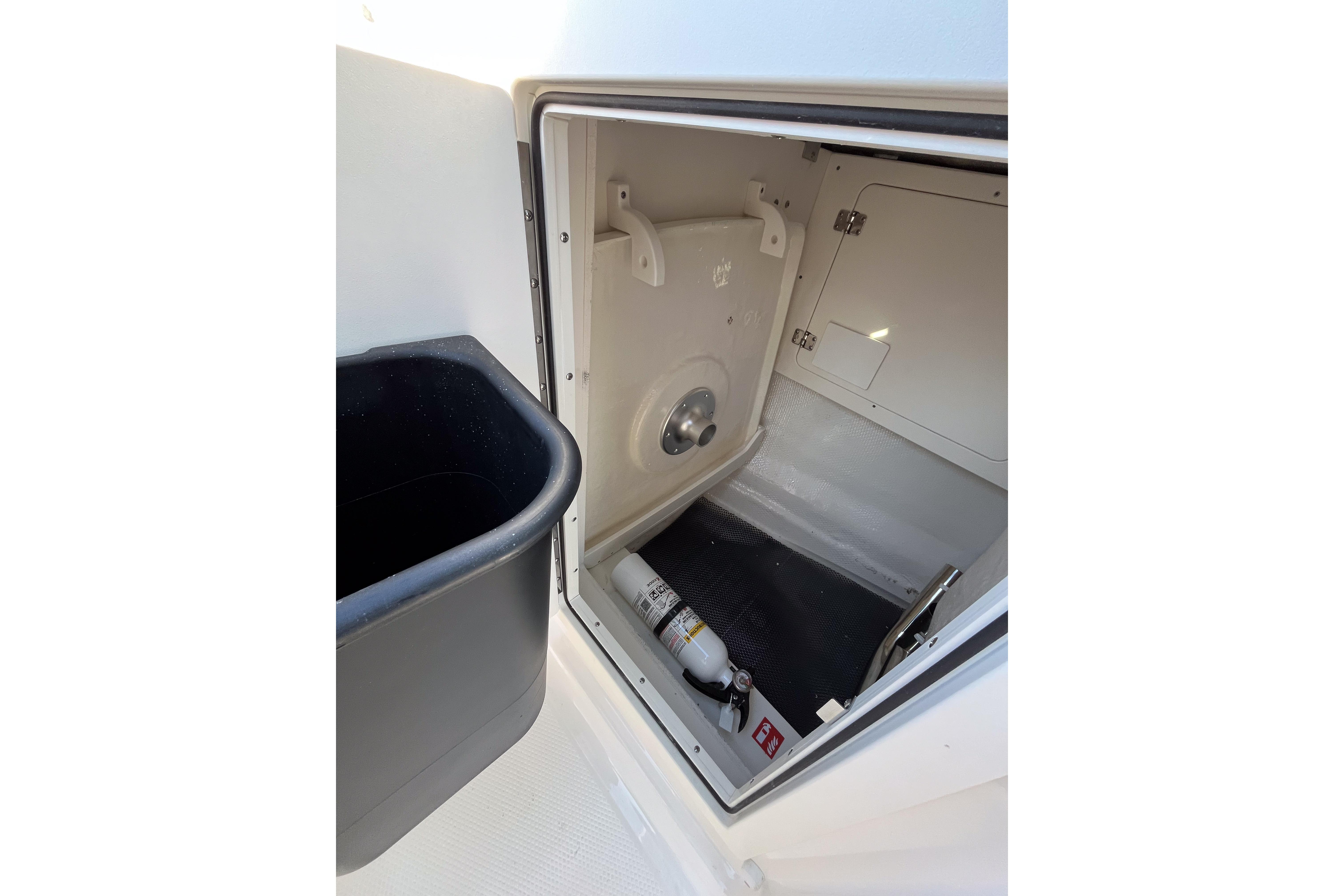 2026 Robalo R257 Dual Console storage compartment with fire extinguisher and trash bin.