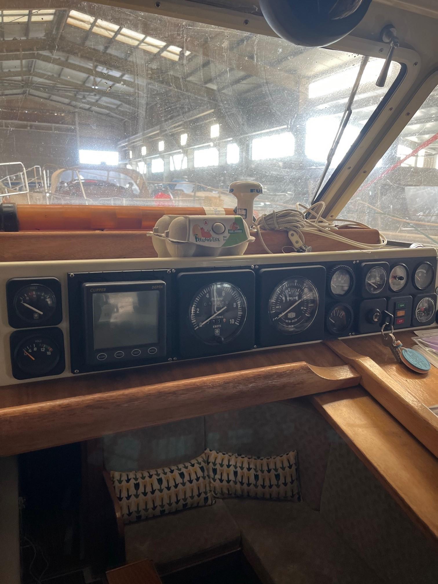 Control panel of a 1980 LM 32 boat, featuring gauges and navigation equipment in a marina setting.